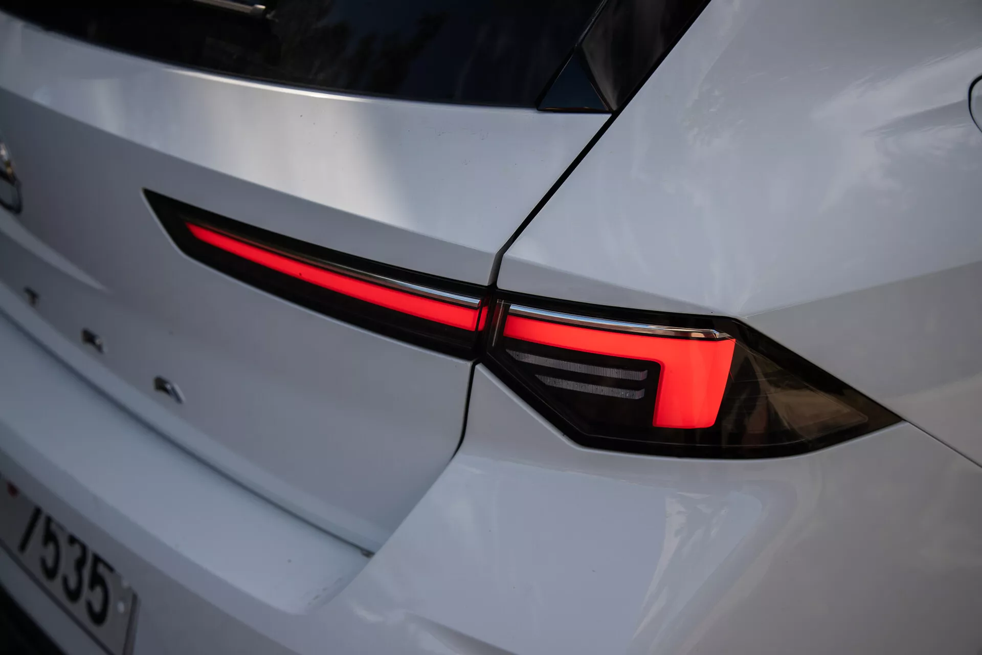 Detail levého zadního světla Opel Astra 2022 s moderním LED designem a integrací do bílé karoserie s sportovním vzhledem