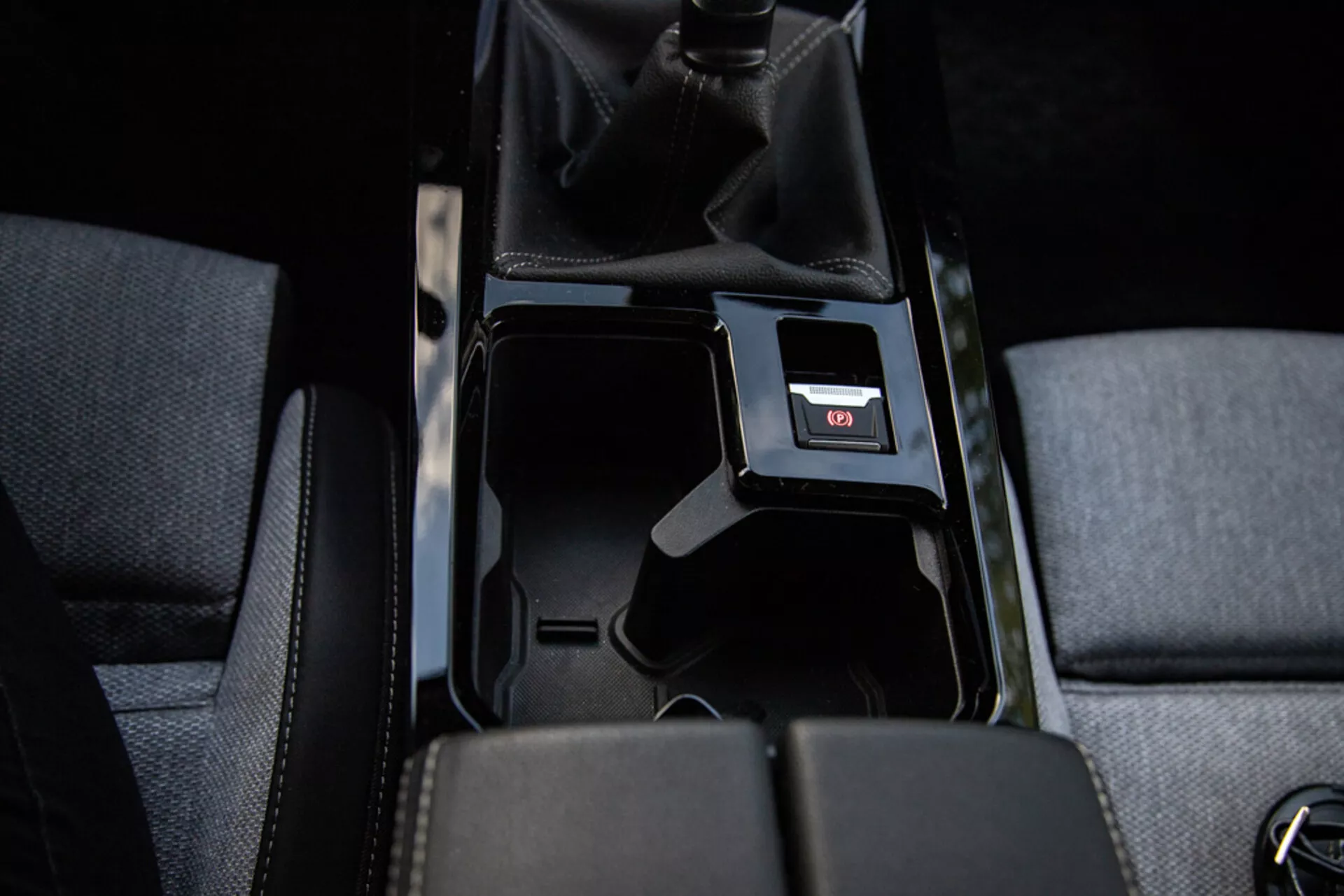 Detail středové konzole Opel Astra 2022 ukazující otevřený úložný prostor, potah sedadel, manuální řadicí páku s perforovanou kůží, USB port a vnitřní osvětlení