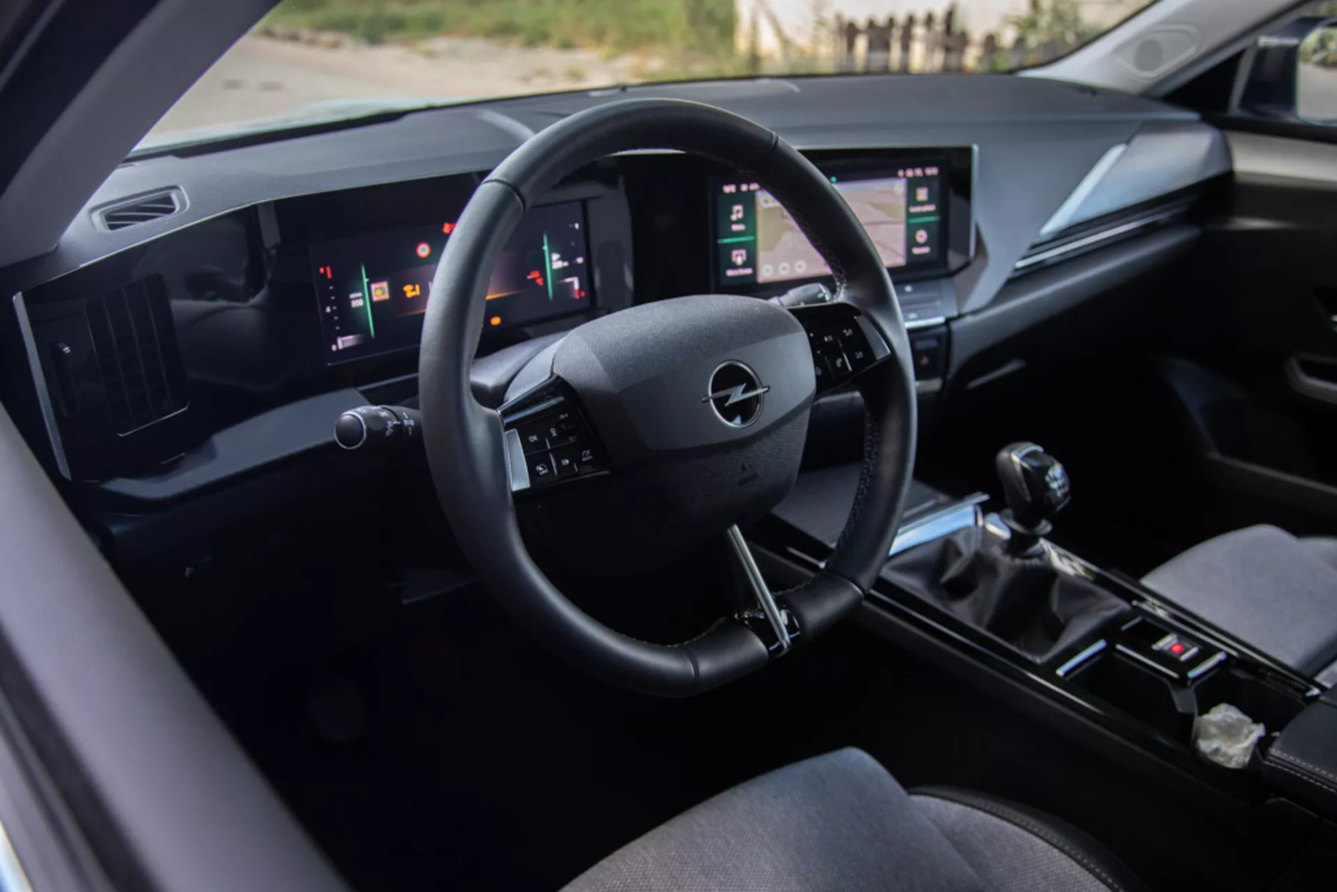 Interiér Opelu Astra 2022 s řidičovým sedadlem, technologicky pokročilým palubním panelem s logem Opelu na volantu, digitálními ukazateli a dvojitými svislými dotykovými panely