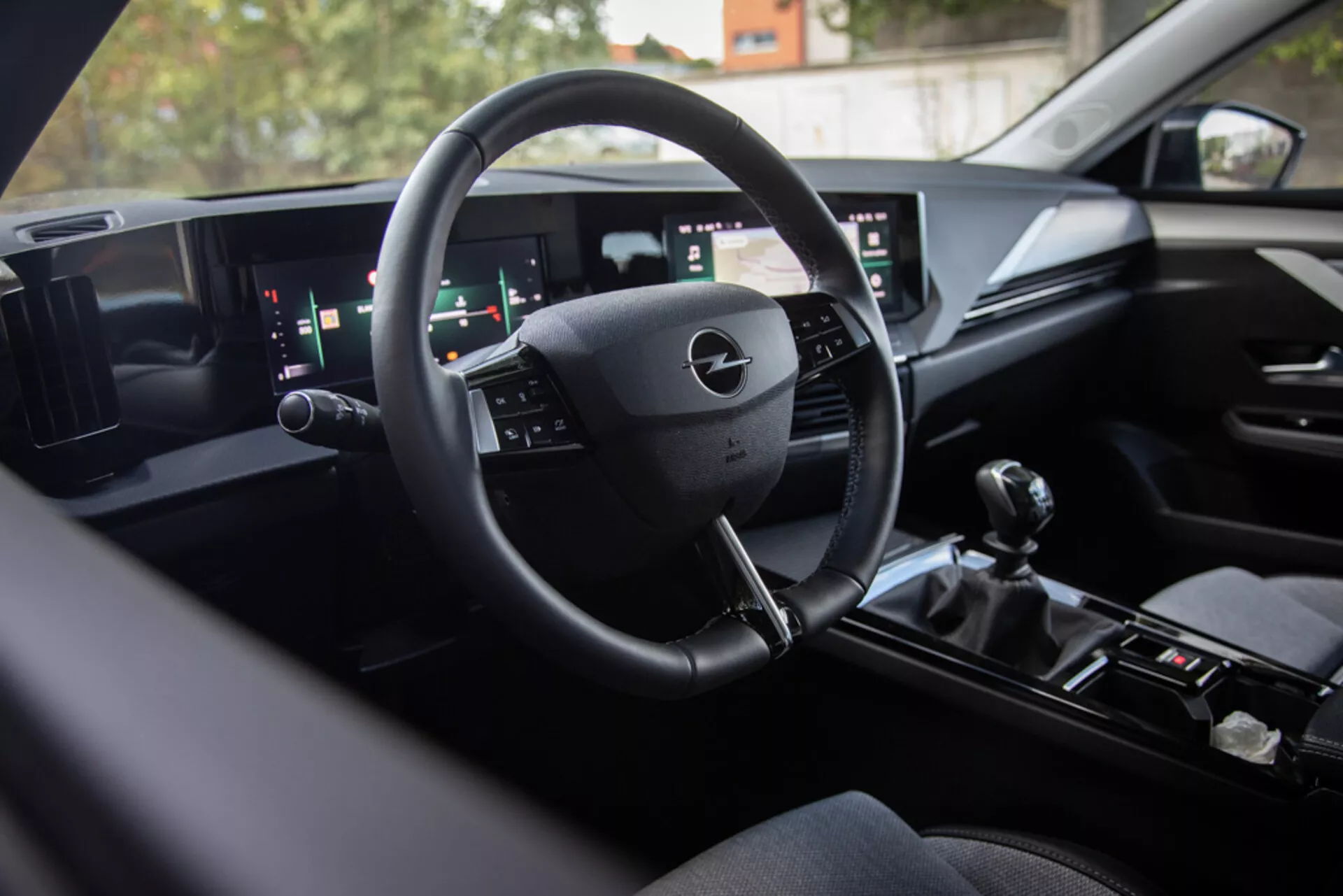 Interiér Opelu Astra 2022 předvádějící moderní technologii digitálního palubního desky, multifunkční volant, široký duální informační systém a manuální řadicí páku pro sportovní výkon, pohled ze zadního sedadla směrem k řidiči s prémiovými povrchovými úpravami
