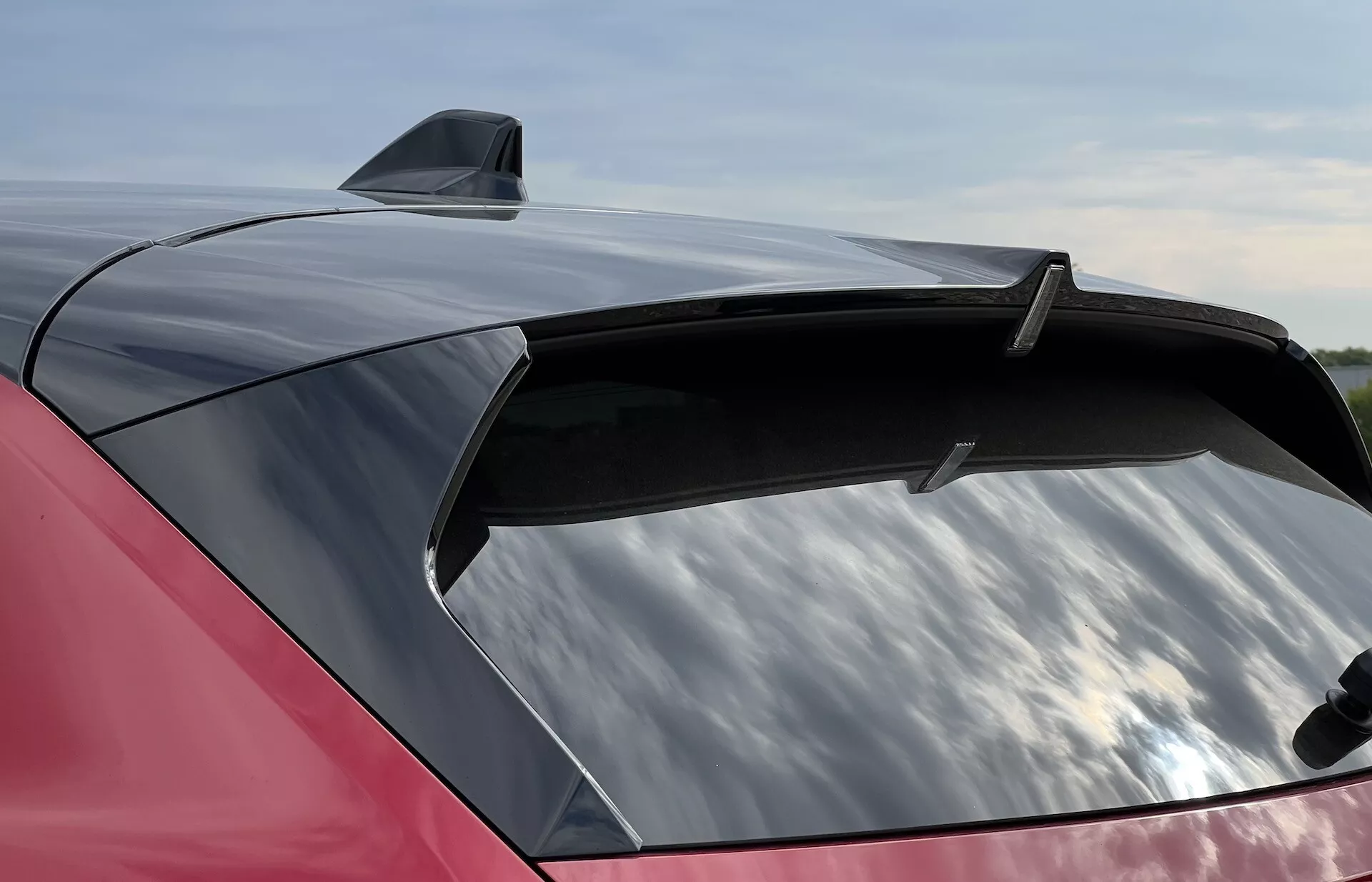 Detailní pohled na zářivě červený zadní díl Opelu Astra 2022 s elegantním spoilerem a žraločí ploutví anténou, zdůrazňuje velké, aerodynamické zadní sklo s potenciální UV ochranou.