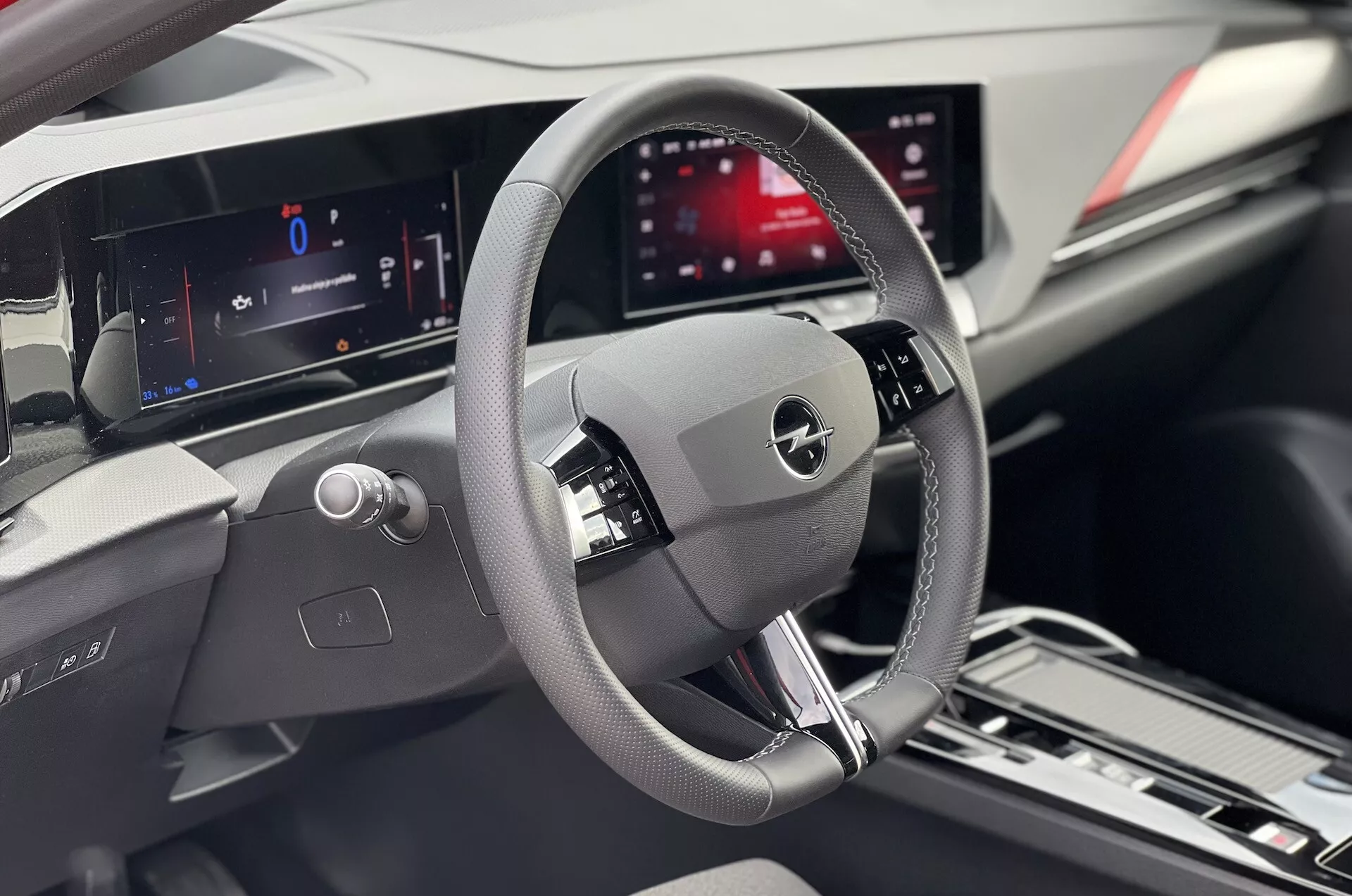 Vnitřní pohled na Opel Astra 2022 se zaměřením na oblast řidiče s detailním volantem, digitálním přístrojovým panelem a centrálním informačním displejem