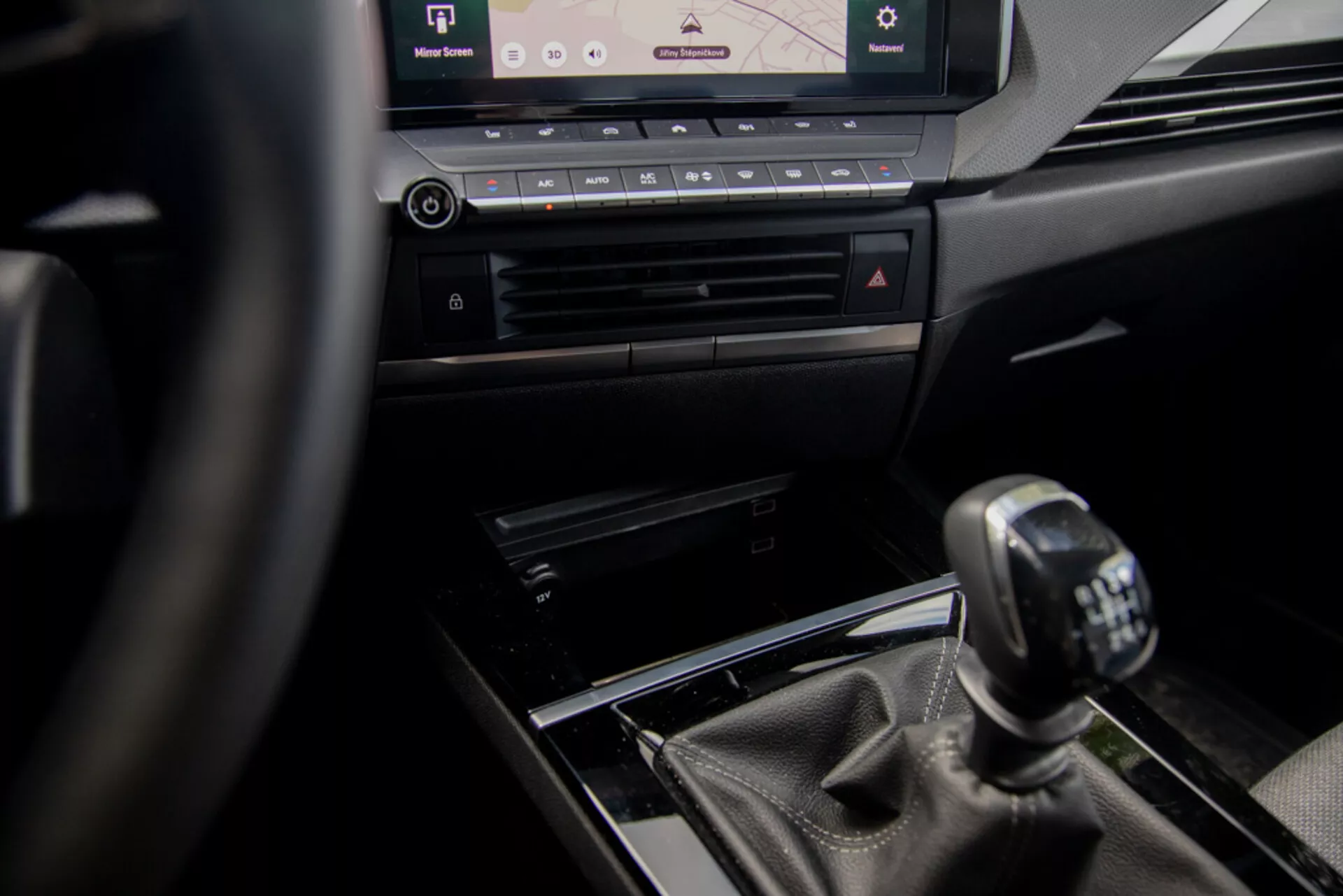 Interiérový pohled na Opel Astra 2022 se zaměřením na středovou konzolu a manuální řazení z perspektivy řidiče, s volantem, luxusními designovými prvky a moderním infotainment systémem.