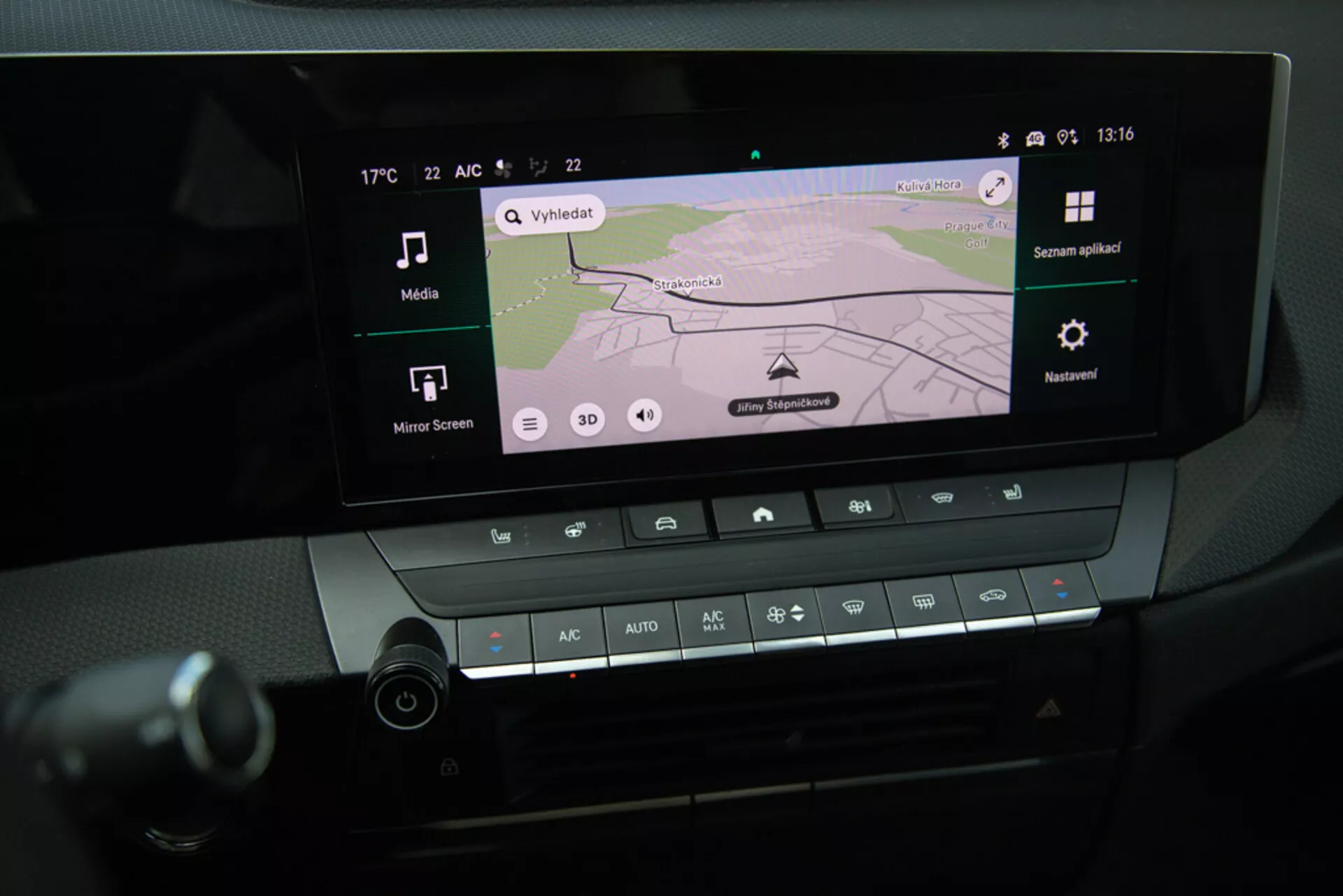 Detailní pohled na infotainment systém a ovládání klimatizace v centrální konzoli Opel Astra 2022, zobrazující GPS navigaci na displeji, Bluetooth konektivitu a nastavení teploty
