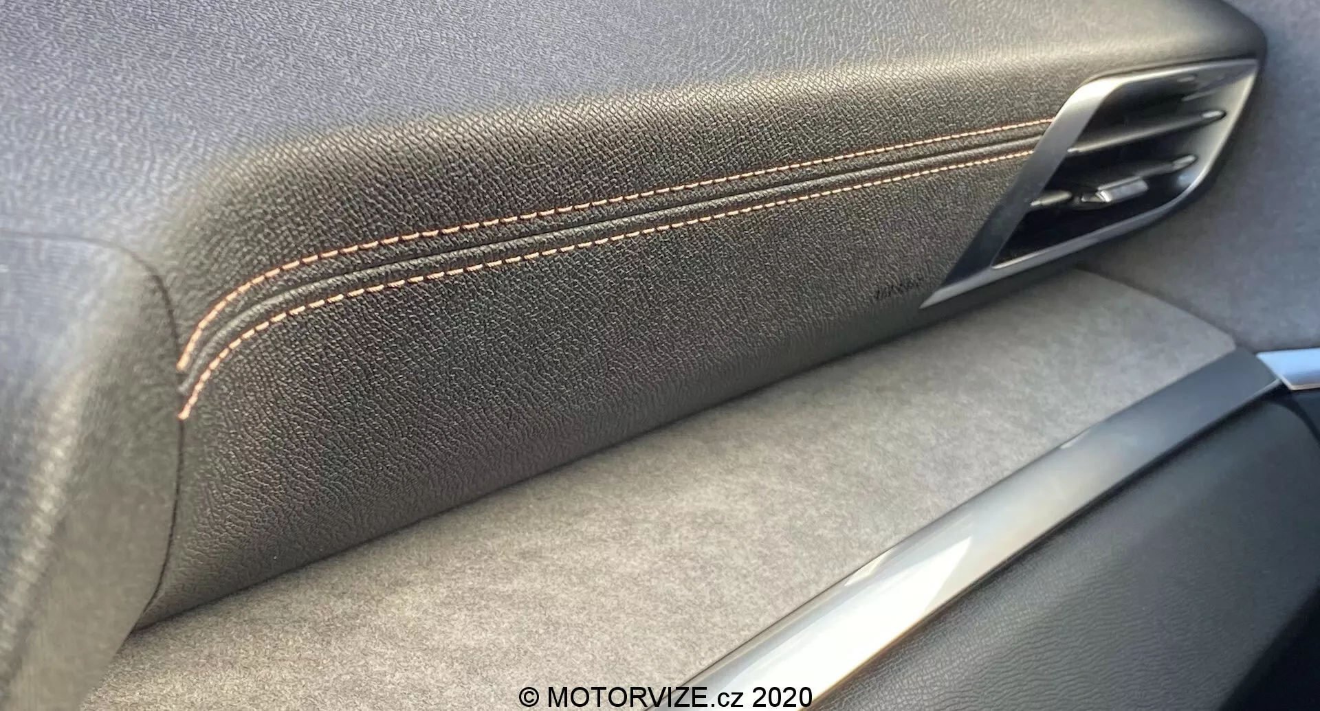Detailní záběr interiéru vozu Peugeot 3008 2021 zaměřený na spojení kožené texturované opěrky s kontrastním prošíváním a kovové kliky dveří. Stříbrné akcenty naznačují důraz na řemeslné zpracování a kvalitu materiálu, stíny naznačují zdroj osvětlení z interiéru.