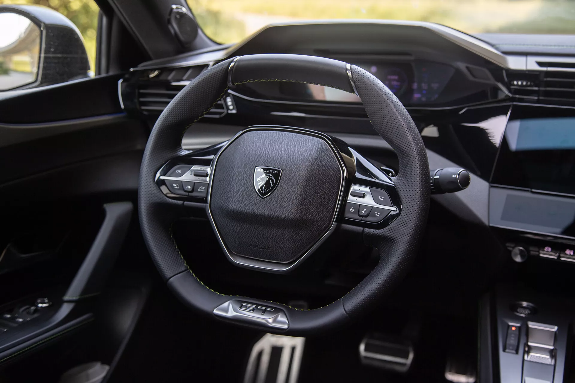 Interiér Peugeotu 408 pro rok 2023 s moderním multifunkčním volantem s logem značky, digitálním palubním panelem v pozadí a částečně viditelnou středovou konzolou s informačním systémem