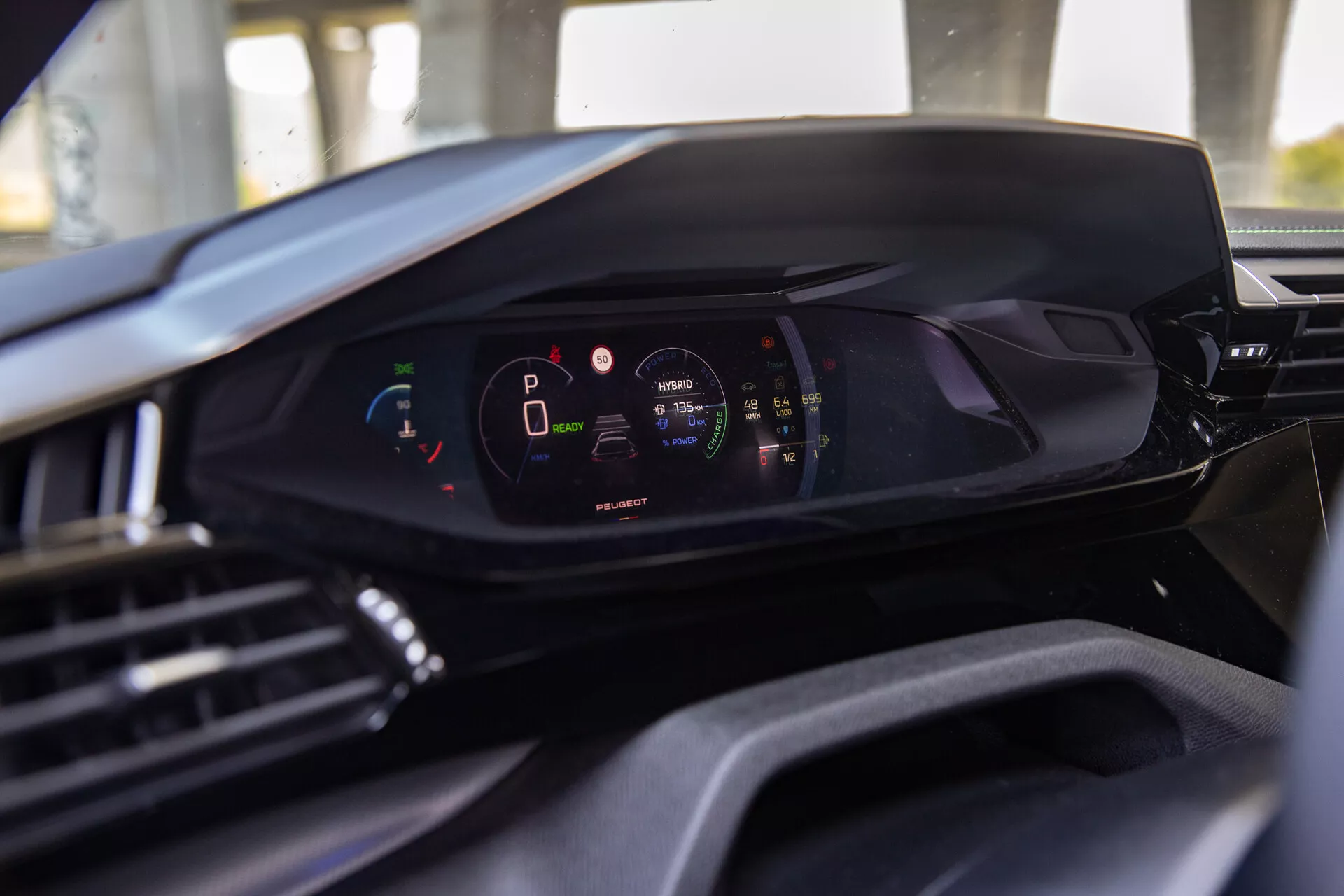 Interiér Peugeot 408 2023 s pohledem na moderní digitální palubní desku z perspektivy řidičova sedadla, zdůraznění digitálního přístrojového panelu s vozidlem v režimu parkování a vysokou úrovní nabití baterie