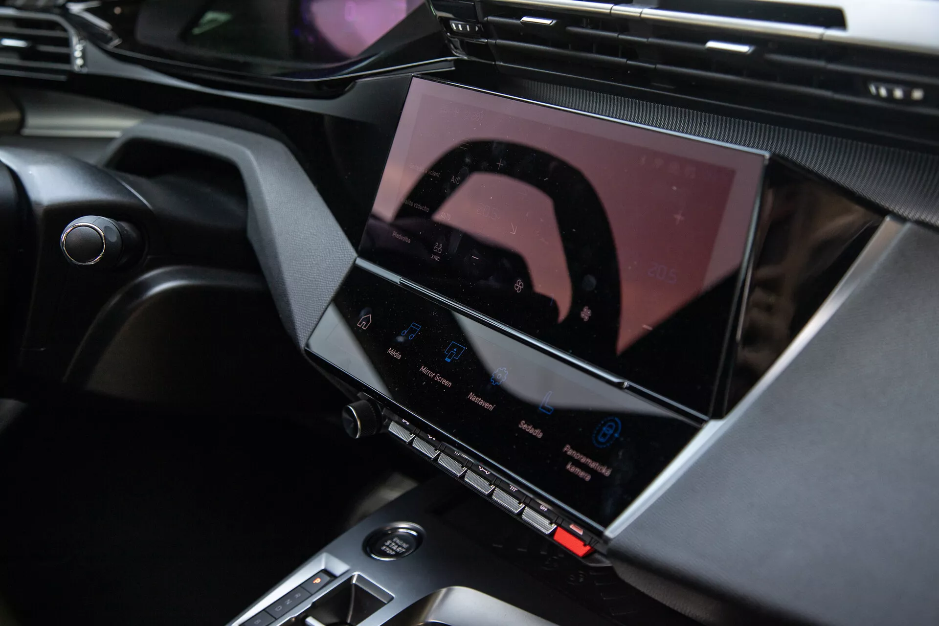 Interiér Peugeot 408 2023 ukazující středovou konzoli a pokročilý informačně-zábavní systém s dotykovým displejem, tlačítky klimatizace a elegantními designovými akcenty