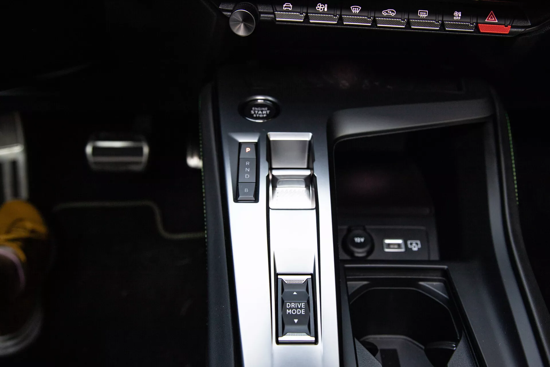 Detailní pohled na středovou konzolu Peugeot 408 2023 s řadicí pákou v poloze Park, tlačítkem DRIVE MODE, elektronickou parkovací brzdou a USB porty, předvádějící moderní design interiéru.
