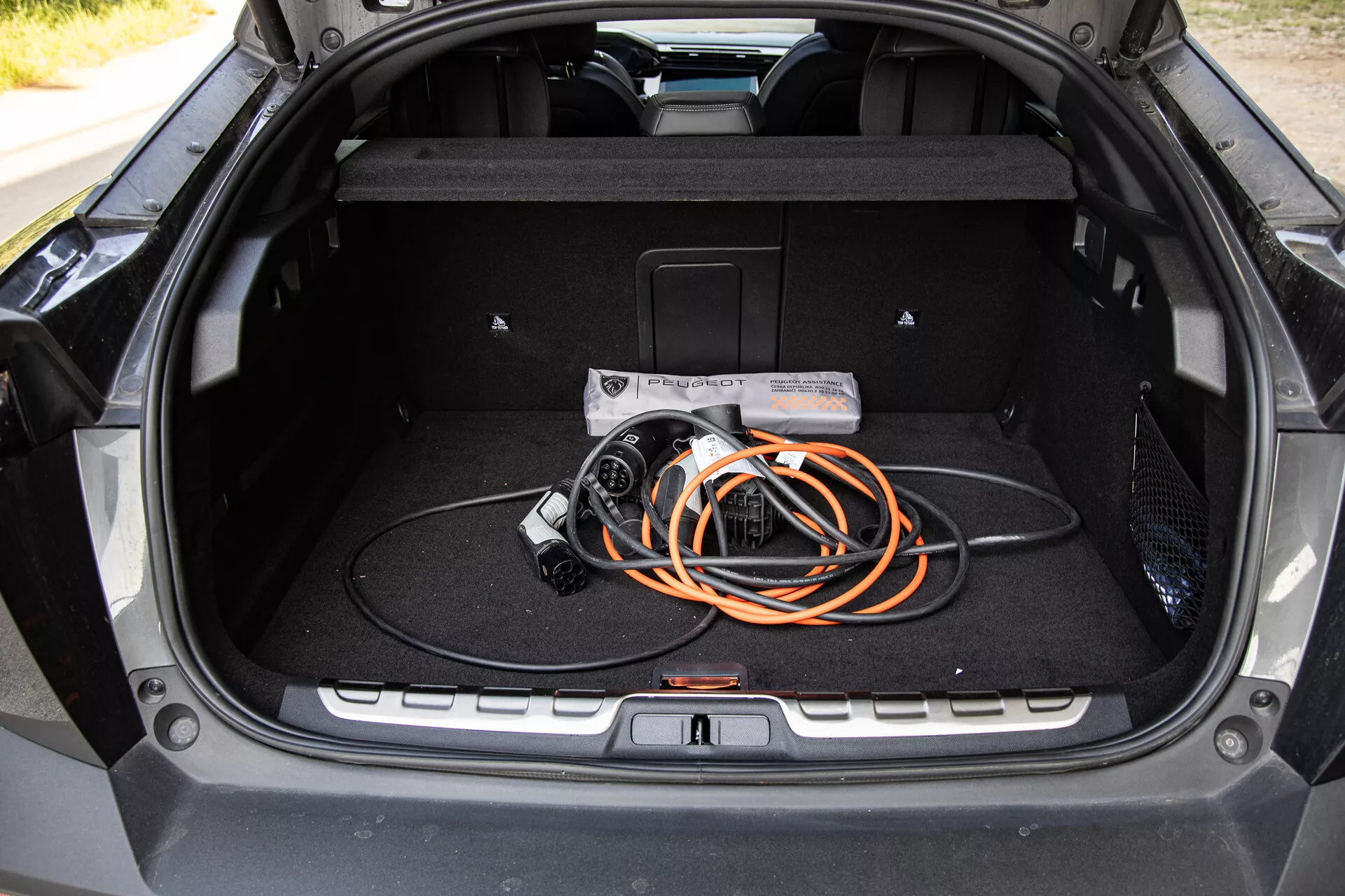Interiér kufru Peugeot 408 2023 s ukázkou prostorného designu a kabelem pro nabíjení elektromobilů, zdůrazněním technologie EV a moderní kvality výroby.