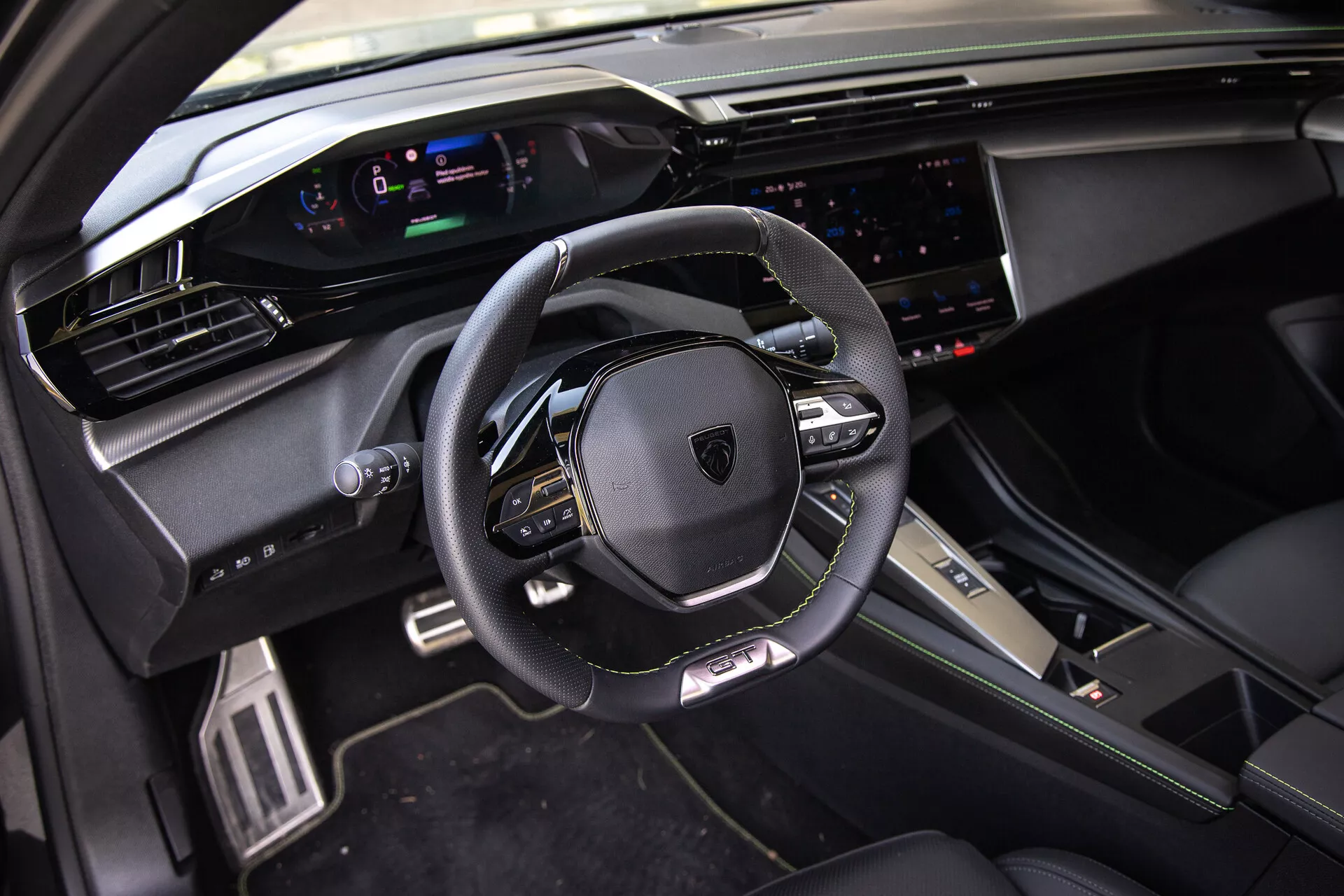 Interiér Peugeotu 408 z roku 2023 s koženým, multifunkčním volantem, digitálním přístrojovým panelem, širokým dotykovým infotainmentsystémem a sportovně prémiovými designovými prvky v přirozeném denním světle z pohledu předního spolujezdce.
