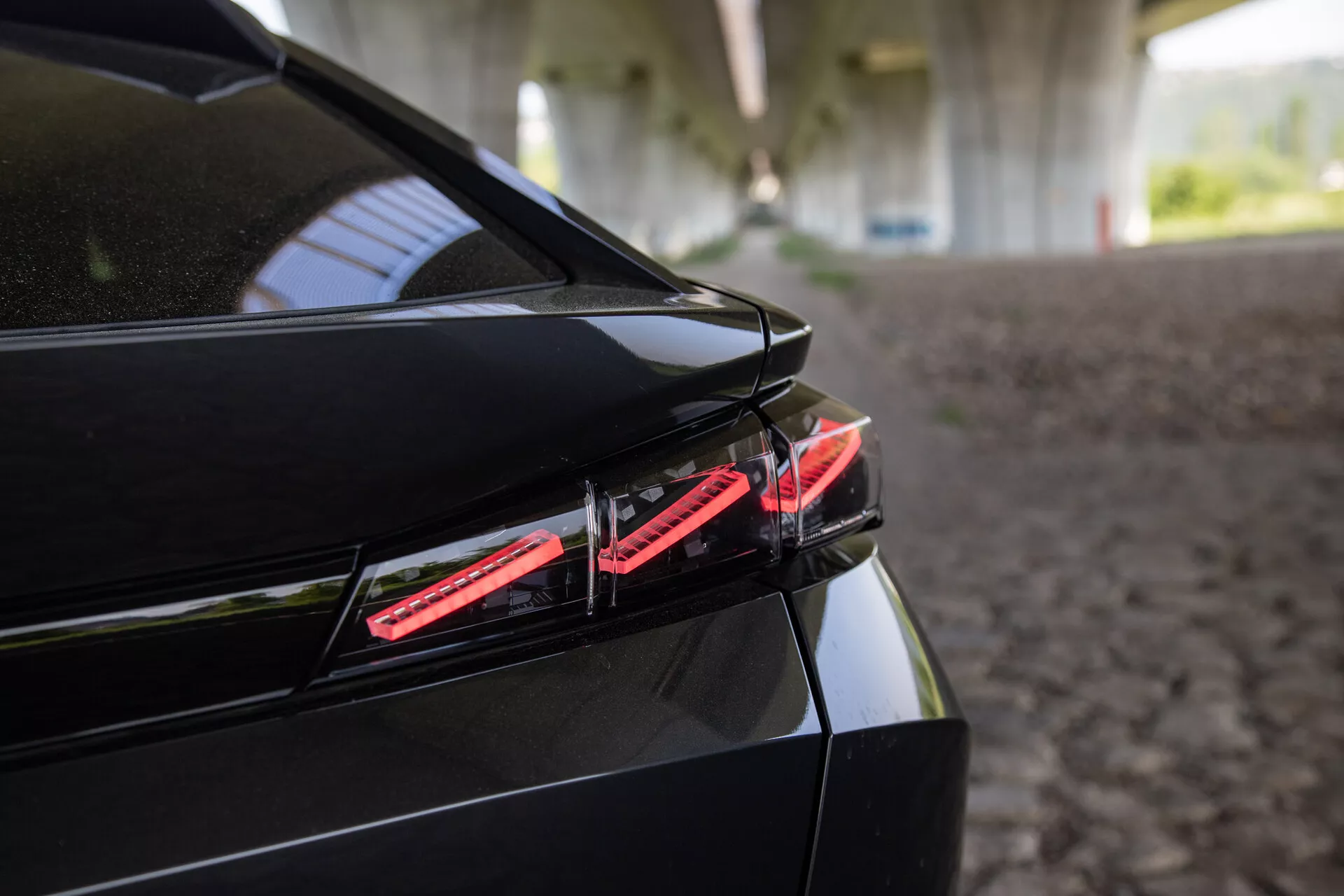 Detailní pohled na zadní část Peugeotu 408 z roku 2023 s LED zadním světlem, elegantním designem kufru se zabudovaným spoilerem a lesklým černým lakem v stínu konstrukce