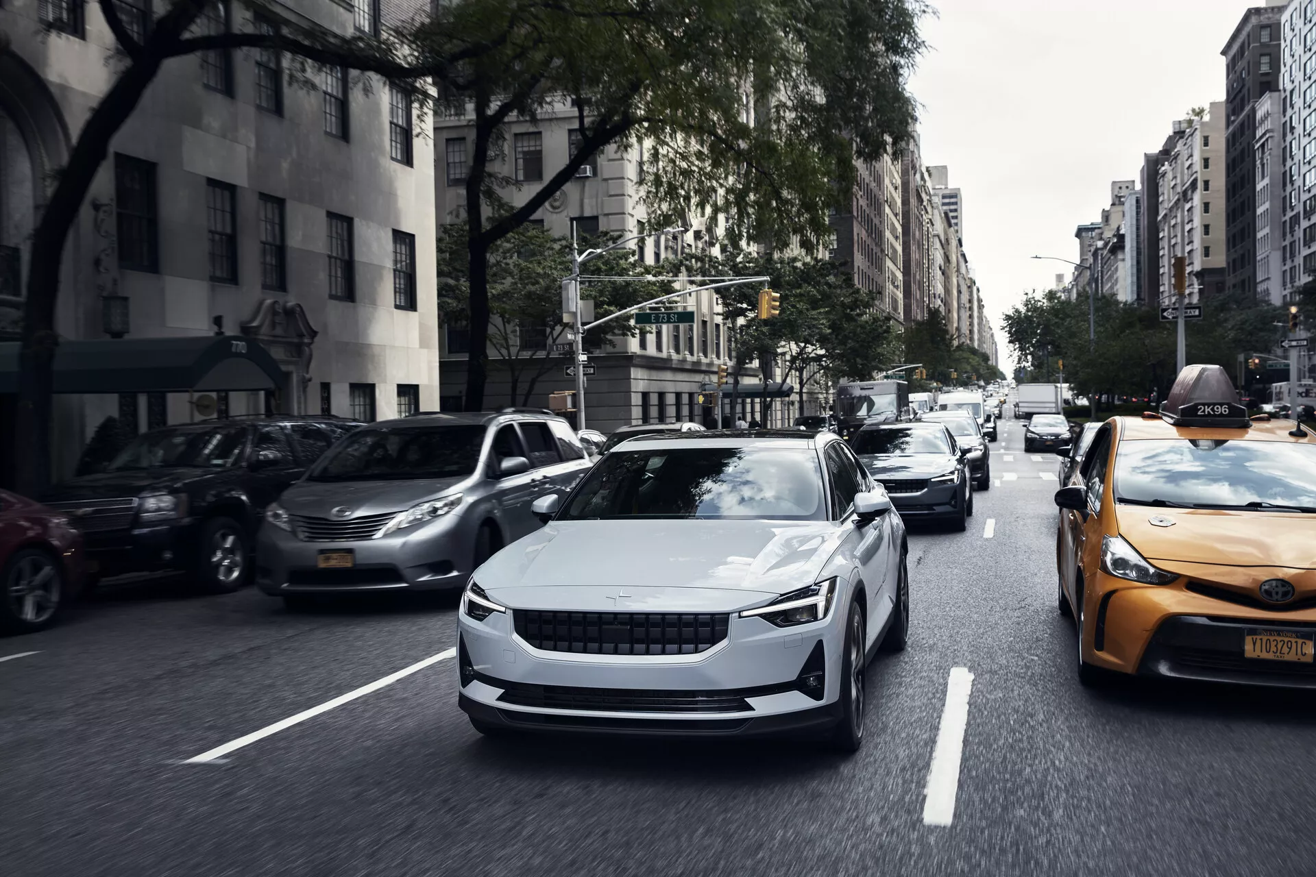 Pohled zepředu na elektrické auto Polestar 2 první generace z roku 2020 v pohybu, který ukazuje jeho elegantní design, aerodynamické křivky a moderní LED světlomety.