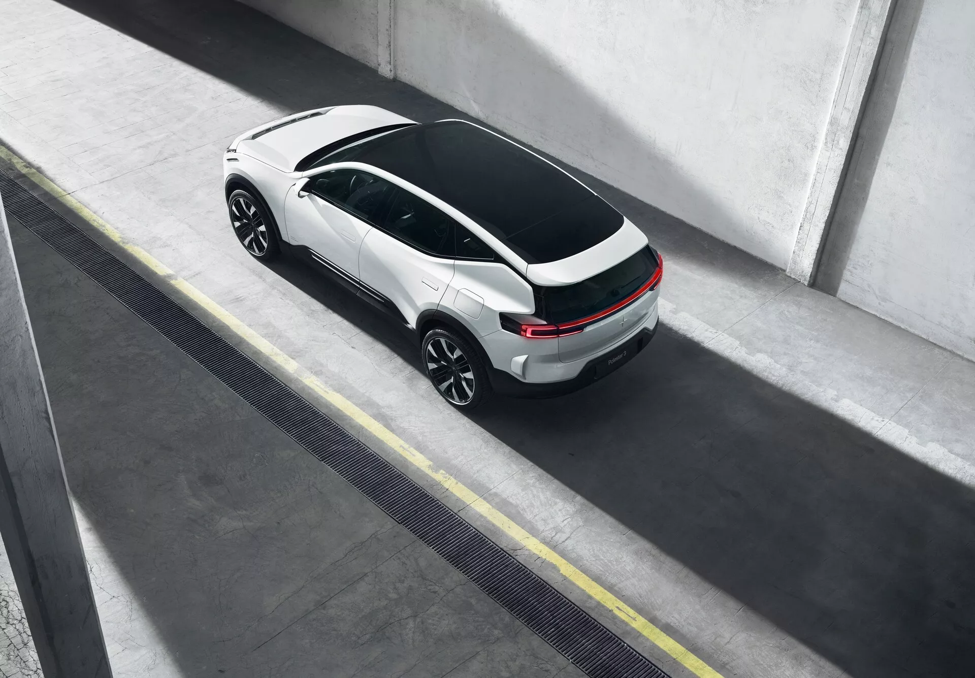 Polestar 3 1. generace z roku 2023 viděn z ptačí perspektivy, parkovaný v městském prostředí s výrazným designem střešního okna a elegantním dvoubarevným barevným schématem
