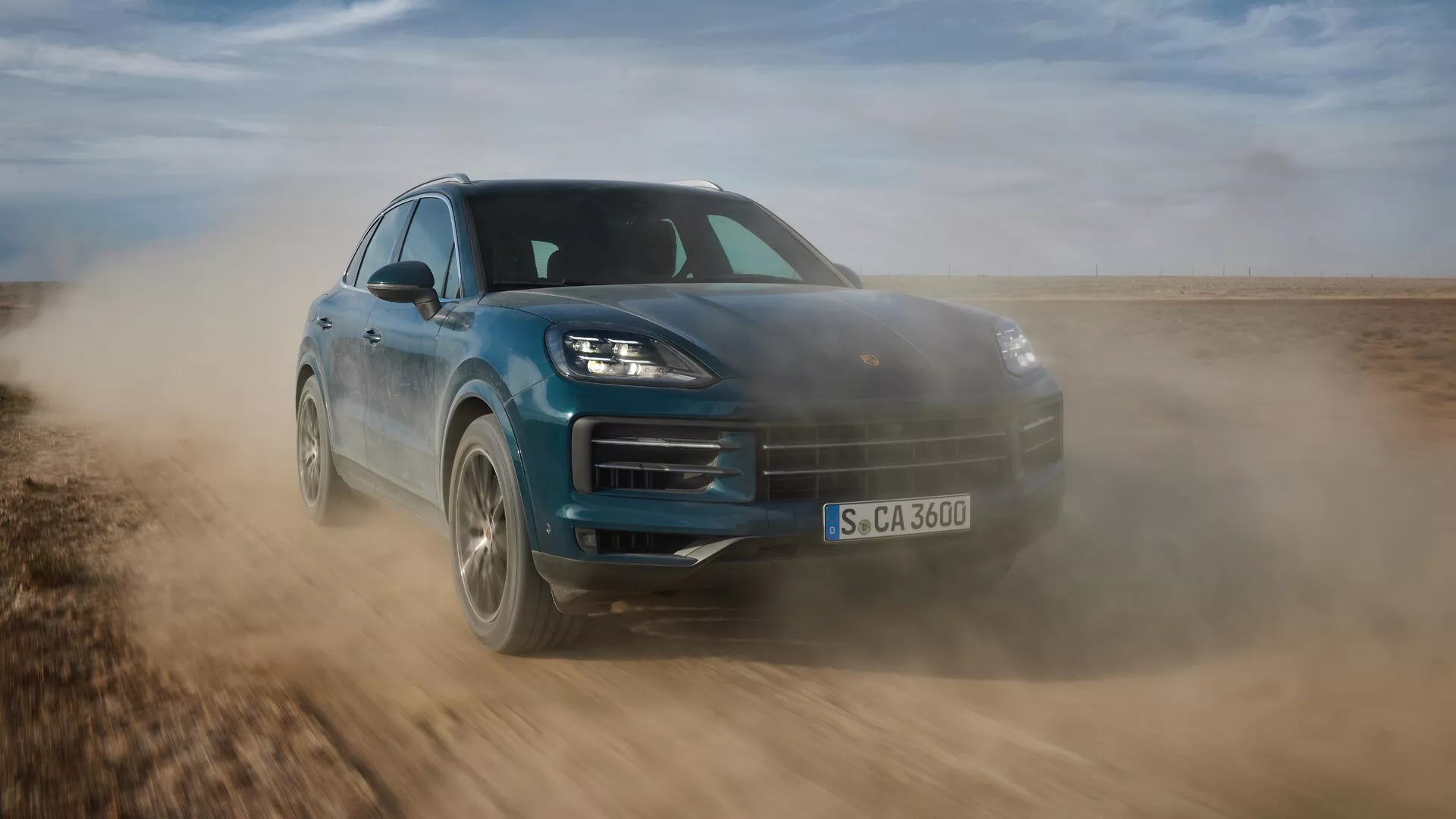 Porsche Cayenne 2023 (facelift 9YA) v dynamickém pohybu, předvádějící svůj elegantní design a schopnosti v terénu, zachycené z nízkého předního tříčtvrtečního úhlu zdůrazňující sportovní postoj, pokročilé LED světlomety a aerodynamické prvky na nezpevněné ploše.