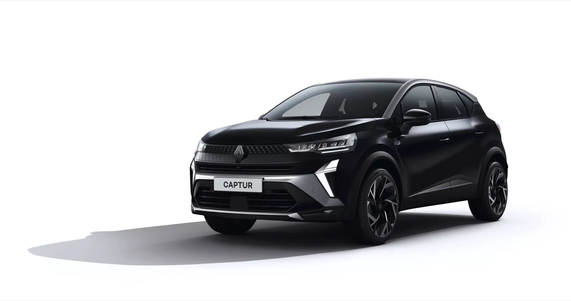 Tříčtvrteční přední pohled na černý Renault Captur 2024, zobrazující štíhlé LED světlomety, výraznou mřížku s centrálním logem, sportovní nárazník s ventilačními otvory, slitinová kola a aerodynamické kontury