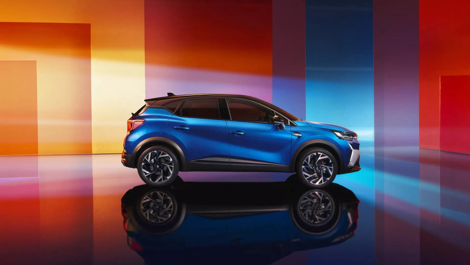 Model Renault Captur II facelift 2024 v metalické modré barvě, ukazující sportovní profil a elegantně navržený předek na odrazové ploše na pozadí s dynamickým přechodem barev