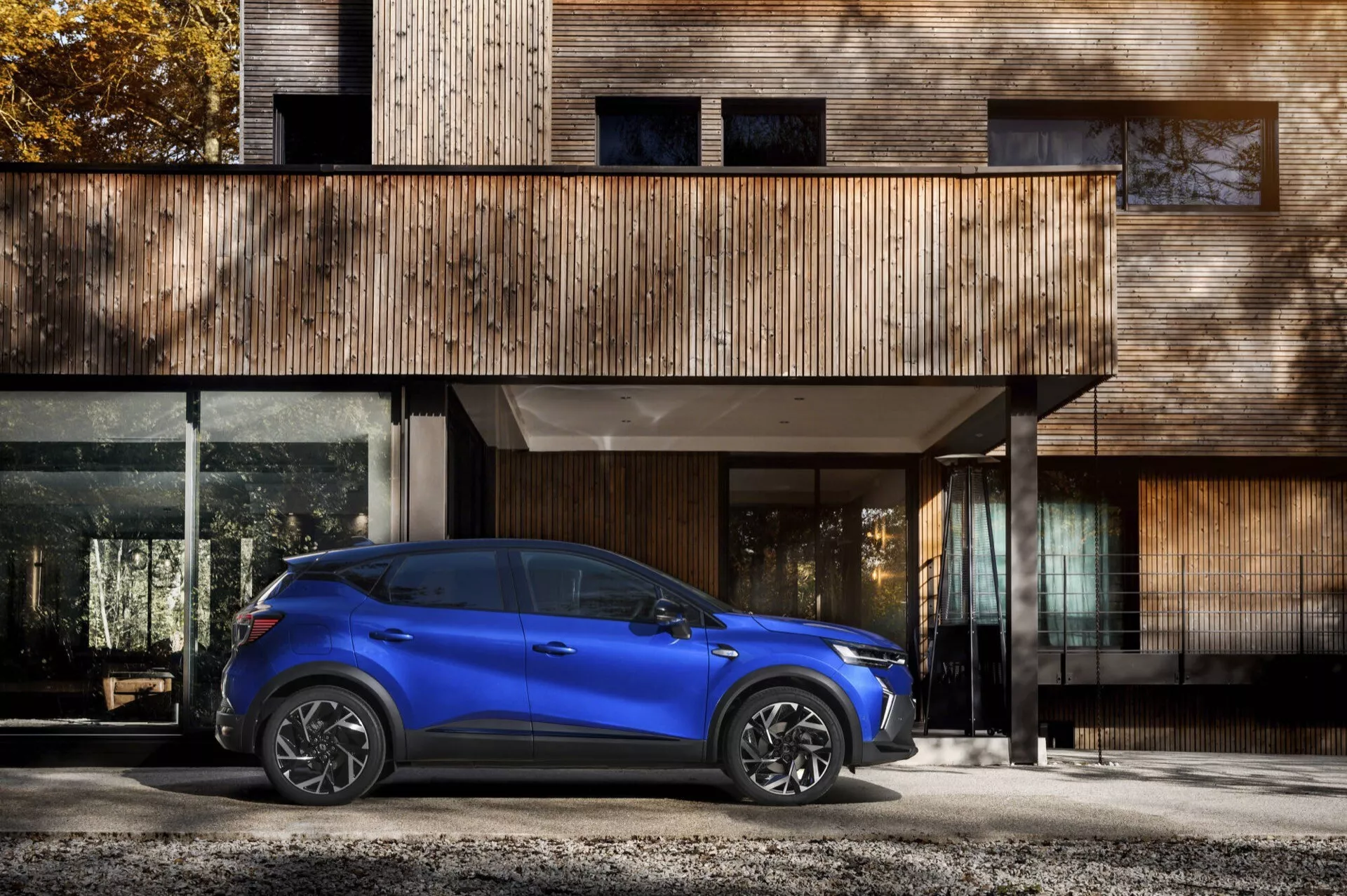 Renault Captur II Facelift 2024 ve světle modré barvě, boční profil s LED světlomety a slitinovými koly před současnou obytnou budovou, předvádějící prvky automobilového designu a osvětlovacího systému
