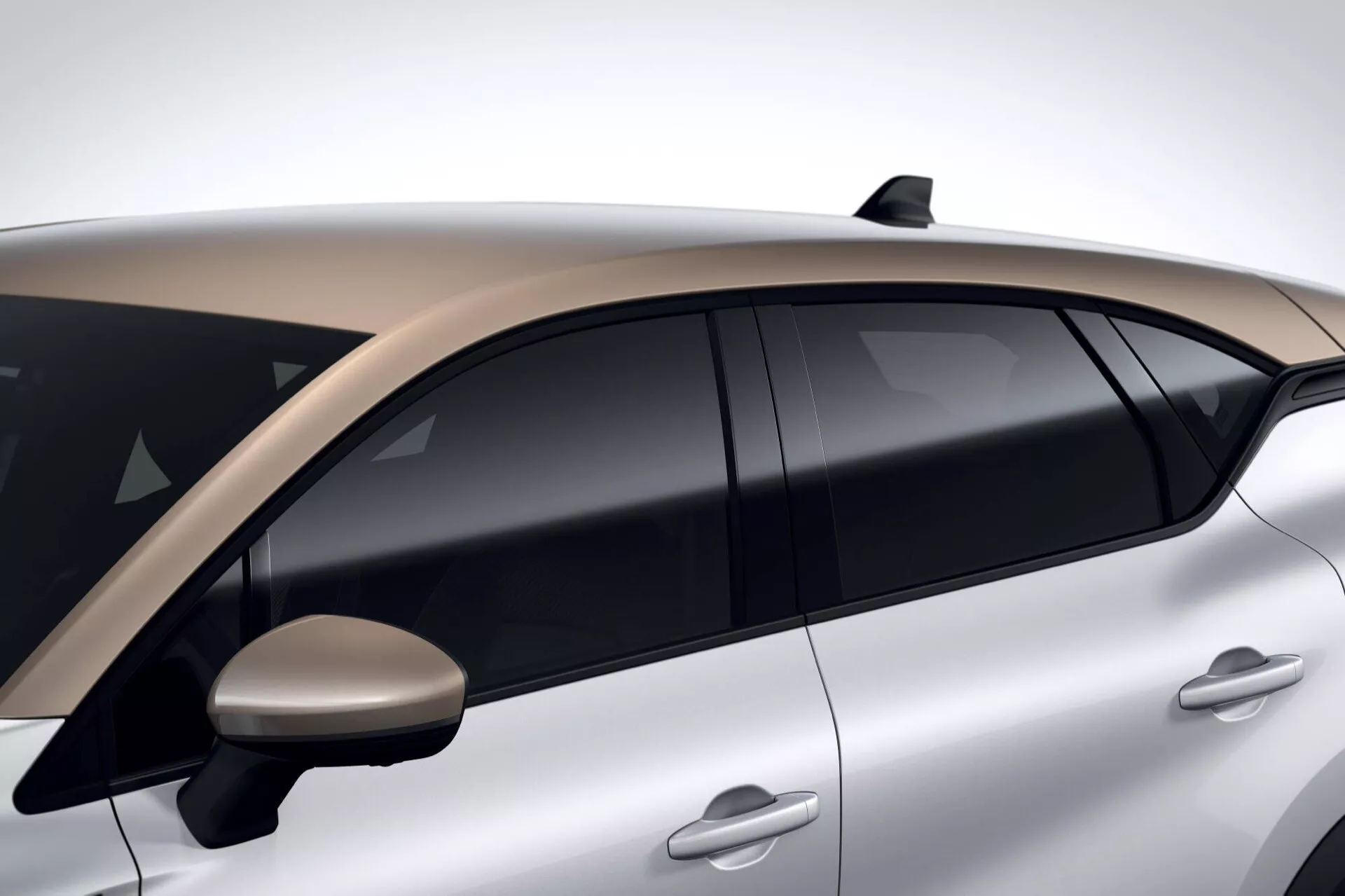 Detailní boční pohled na Renault Captur 2024 II-Facelift ukazuje aerodynamické kličky dveří, tónovaná okna, dvoubarevnou střechu, aerodynamické boční zrcátko, žraločí ploutev anténu a metalické stříbrné provedení