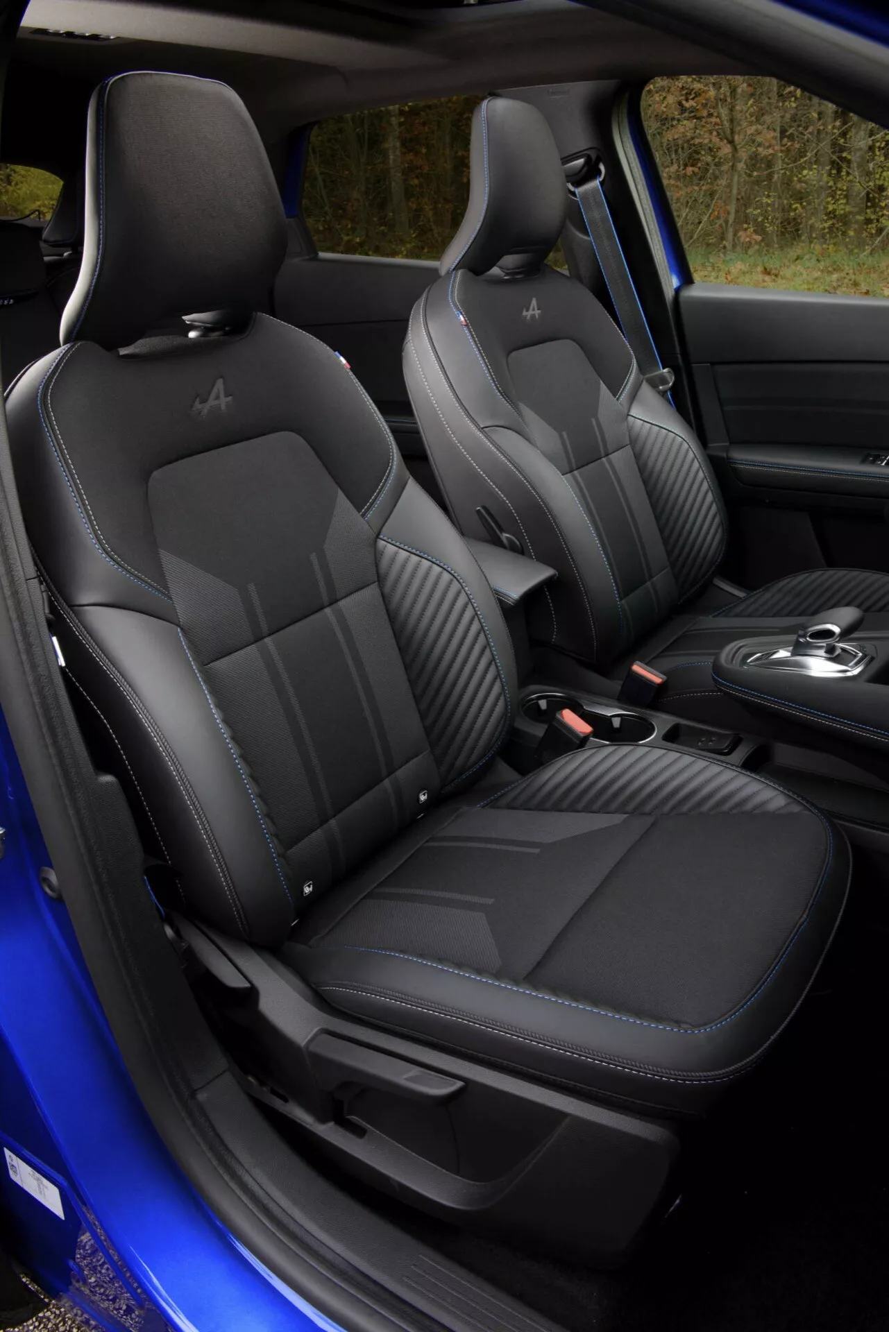 Interiérový pohled na model Renault Captur II facelift 2024, zdůrazňující prémiová černá kožená sedadla s prošíváním do kvadratu, vyraženými opěrkami hlavy a sportovně orientovanými bočními opěrkami, včetně náhledu na páku automatického řazení a luxusní detaily kabiny v tmavých tónech.