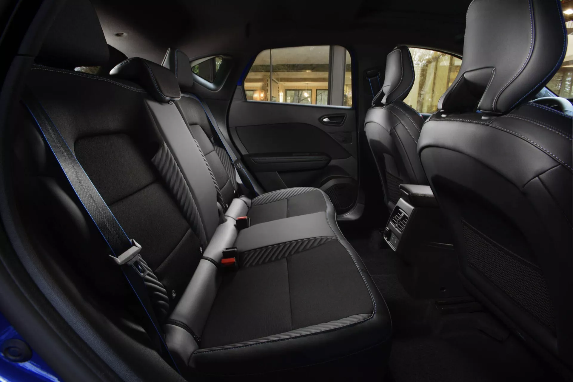 Interiér Renault Captur 2024 (II-facelift) s výhledem na luxusní zadní část pro cestující s černými koženými sedadly, ambientním osvětlením a pokročilým klimatizačním systémem, záběr z výšky