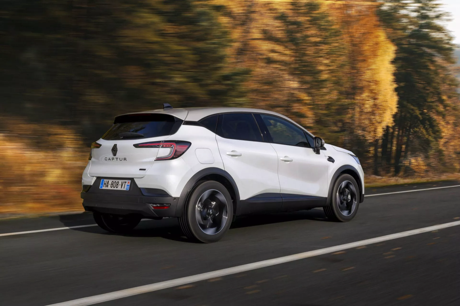 Facelift Renault Captur 2024 v bílé barvě, dynamický pohled zezadu a ze strany ukazující pokročilé LED zadní světla, sportovní černé ráfky a střešní okno