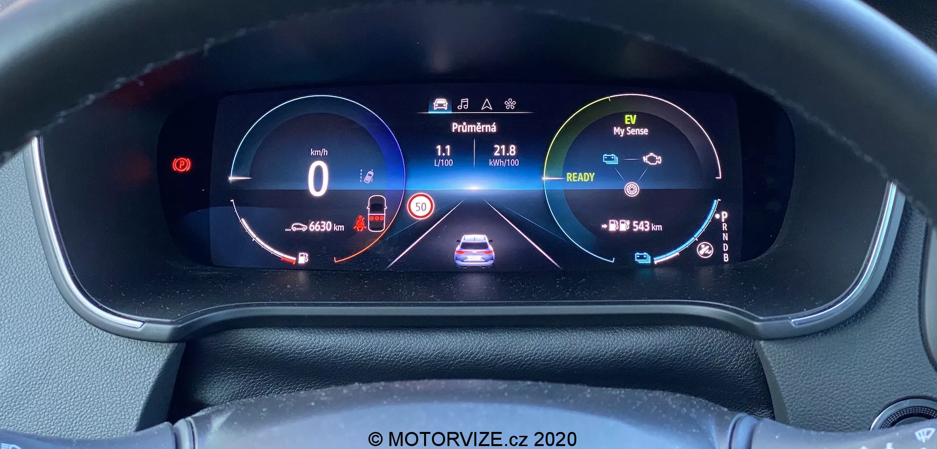 Pohled zblízka na plně osvětlenou digitální palubní desku Renault Megane E-Tech 2022 z pozice řidiče, obsahující tachometr ukazující 0 km/h, indikátor baterie, centrální grafické zobrazení vozu s parkovacím asistenčním symbolem, otáčkoměr, počítadlo ujetých kilometrů ukazující 4660 km, venkovní teplotu 21,8°C, dojezdový indikátor baterie s dojezdem 548 km a další ikony systémů vozidla