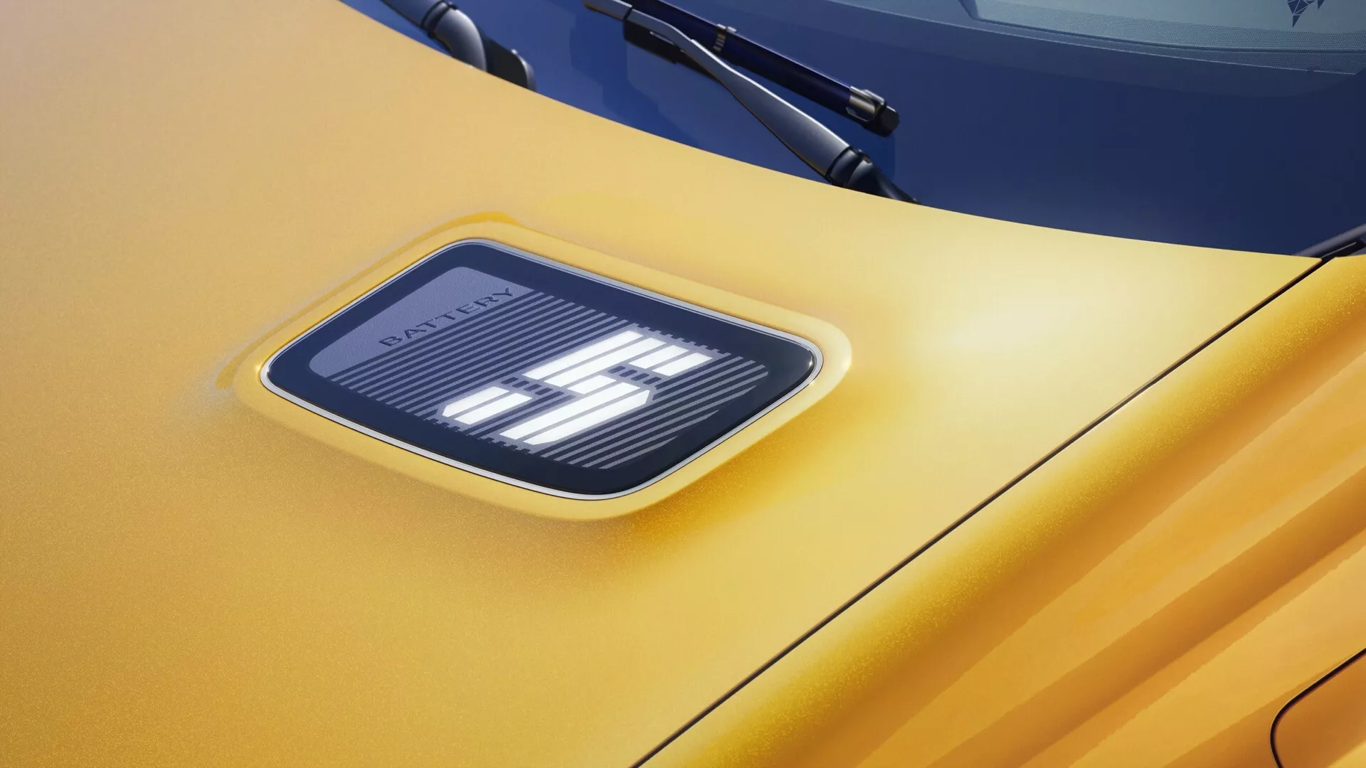 Detailní pohled na emblém Renault R5 2024 s osvětlenými prvky na žluté kapotě, prezentující pokročilou technologii LED osvětlení a moderní design vozidla