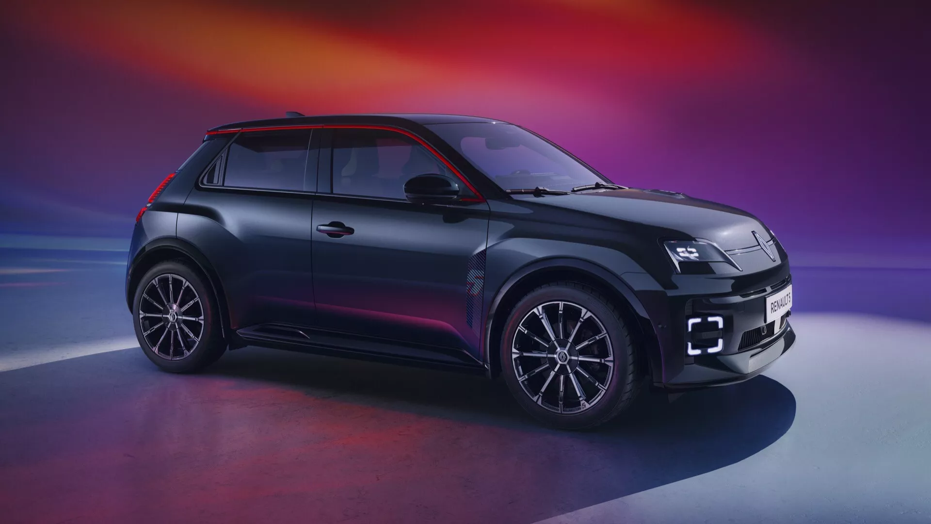 Pohled zepředu na bok Renaultu R5 2024 ukazující LED světlomety, unikátní mřížku chladiče, slitinová kola s více paprsky, kompaktní SUV karoserii s dvoubarevným lakem a aerodynamický design na pozadí s gradientem fialové a oranžové