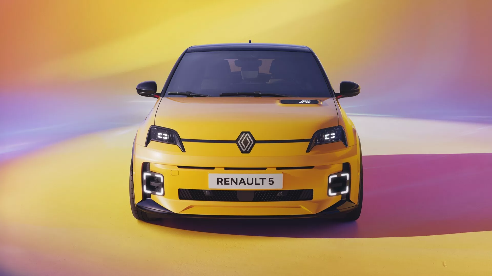 Pohled zepředu na žlutý Renault R5 rok 2024 s LED světlomety, centrální mřížkou s logem Renault a detailními designovými prvky na pozadí s přechodem.