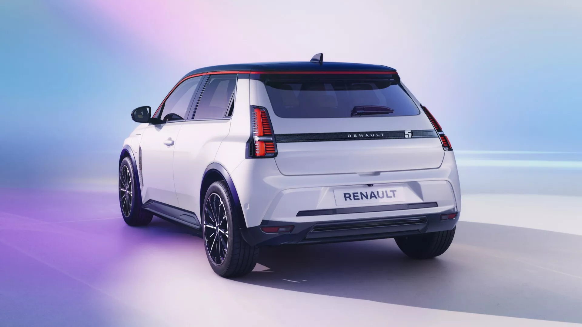 Zadní tříčtvrteční pohled na bílé SUV Renault R5 2024 na přechodovém pozadí z růžové do modré, zdůrazňující moderní design vozidla s LED zadními světly, černými ochrannými lemy, tmavými slitinovými koly, spoilerem na střeše a žraločí ploutví anténou, v podmínkách studiového osvětlení.