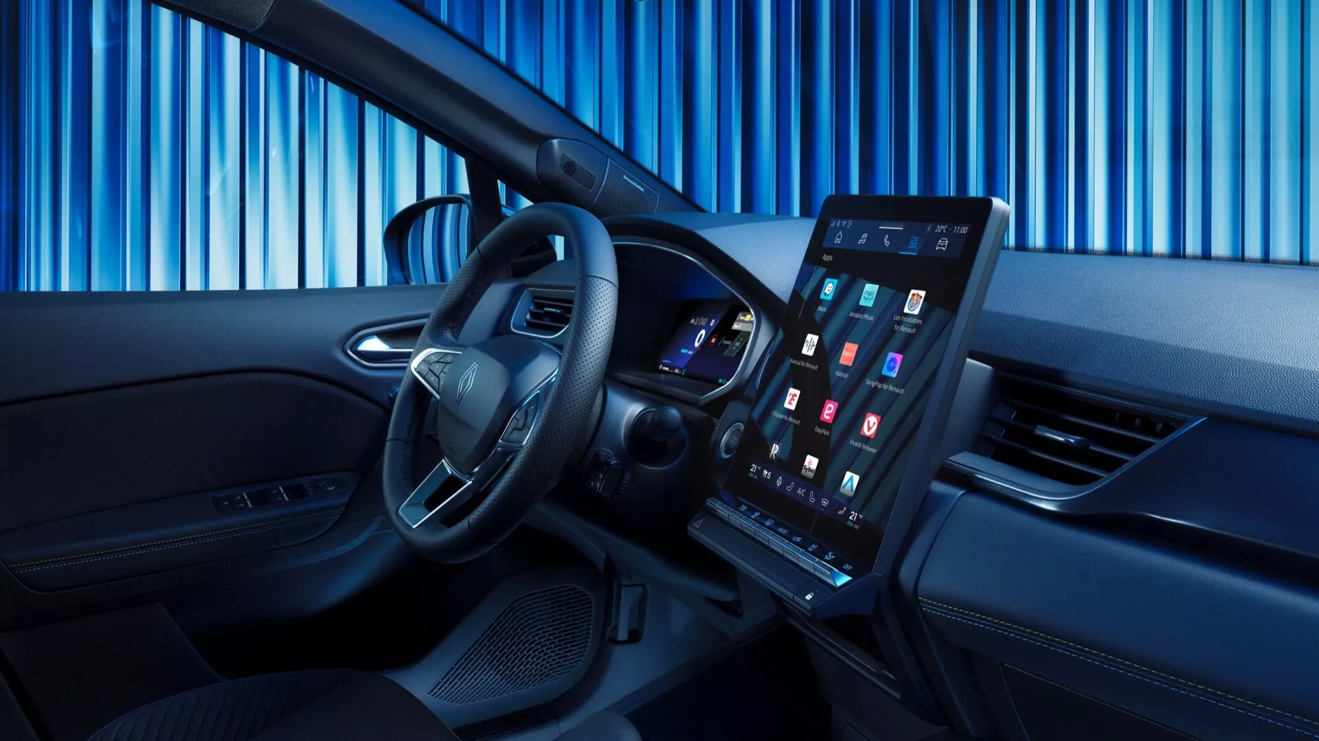 Obrázek představuje interiér Renaultu Symbioz 2024 (1. generace), který se vyznačuje moderním a sofistikovaným designem. Snímek je pořízen z mírně vychýleného úhlu směrem k přednímu sedadlu spolujezdce, což poskytuje jasný pohled na řidičský prostor. Ve popředí je výrazný volant se stříbrnými akcenty a ovládacími tlačítky. Za volantem je vidět digitální přístrojová deska s barevným displejem. Střední část přístrojové desky dominuje velký, vertikálně orientovaný dotykový infotainment systém. Kabina má dvoutónový interiér s vysoce kvalitními materiály, úzkým větracím otvorem pod obrazovkou a ovládacími panely na dveřích řidiče.