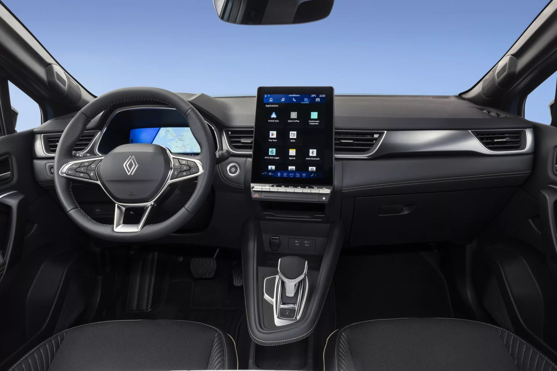 Pohled do interiéru vozu Renault Symbioz 2024 z předního sedadla spolujezdce, představuje multifunkční tříramenný volant s ovládacími prvky, jasný digitální přístrojový panel a velký portrétně orientovaný dotykový infotainment displej integrovaný do středového panelu. Čistá a moderní středová konzole zahrnuje minimalistický dotykový ovládací panel pro nastavení klimatizace a moderní elektronický řadicí volič, spolu s viditelnými držáky na nápoje. Vozidlo se vyznačuje elegantním designem s prémiovými materiály a sladěnými dveřními panely, zaměřuje se na pokročilé automobilové technologie, digitální přístroje a uživatelský komfort.