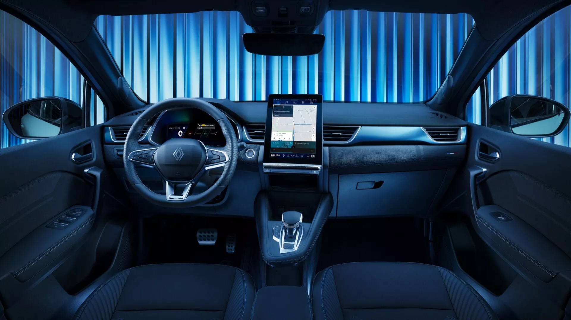 Interiér modelu Renault Symbioz 2024, první generace, focený ze středu zadní části, zobrazující elegantní přední přístrojovou desku, multifunkční volant s ovládacími tlačítky, digitální přístrojovou desku, velkou vertikální dotykovou obrazovku pro infotainment, minimální fyzické ovládací prvky, elektronický volič převodovky, držáky na nápoje, tmavě čalouněná sedadla s detailním prošíváním, odrážející vysoce technologický a moderní design.