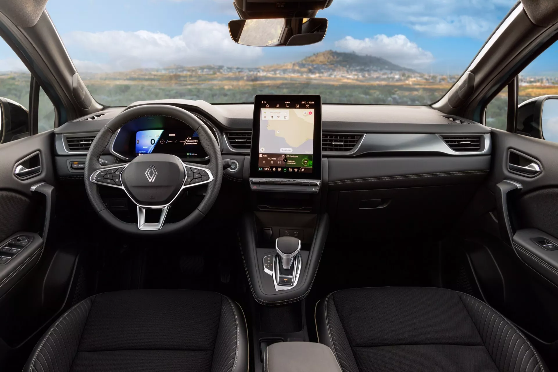 Záběr interiéru Renault Symbioz 2024 první generace z pohledu zadních sedadel, zobrazující přístrojovou desku a přední sedadla. Obsahuje centrálně umístěný volant s plochým dnem a multifunkčními ovladači, digitální přístrojovou desku, velký dotykový infotainment systém, minimalistické ovládání klimatizace, elegantní řadící páku a kožená sedadla s konturováním, zdůrazňující moderní design a pokročilou technologii.