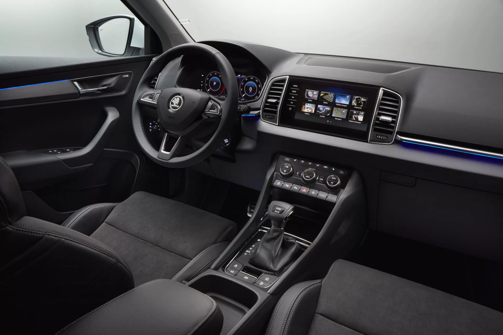 Interiér Škoda Karoq 2017 s multifunkčním koženým volantem s logem, digitálním přístrojovým panelem, dotykovým informačním systémem, klimatizací s dvěma zónami, automatickou voličkou rychlostí, ambientním osvětlením, ergonomickými koženými sedadly a ovládáním elektrických oken.