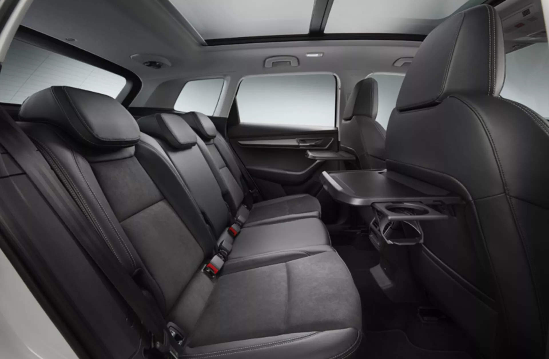 Detailní pohled na luxusní zadní část cestujícího prostoru Skoda Karoq 2017, předvádějící kožená sedadla, zábavní systém, panoramatickou střechu a funkce klimatizace