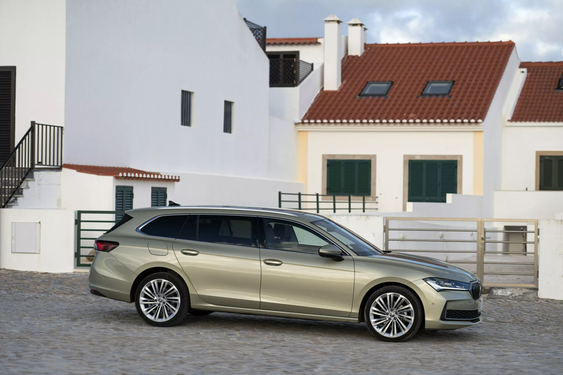 Škoda Superb Combi 2024 zachycená z boční perspektivy, předvádějící celé karosérie typu kombi, prodlouženou střechu, litá kola s vícepaprskovým designem a prémiové chromové lišty v evropském městském prostředí