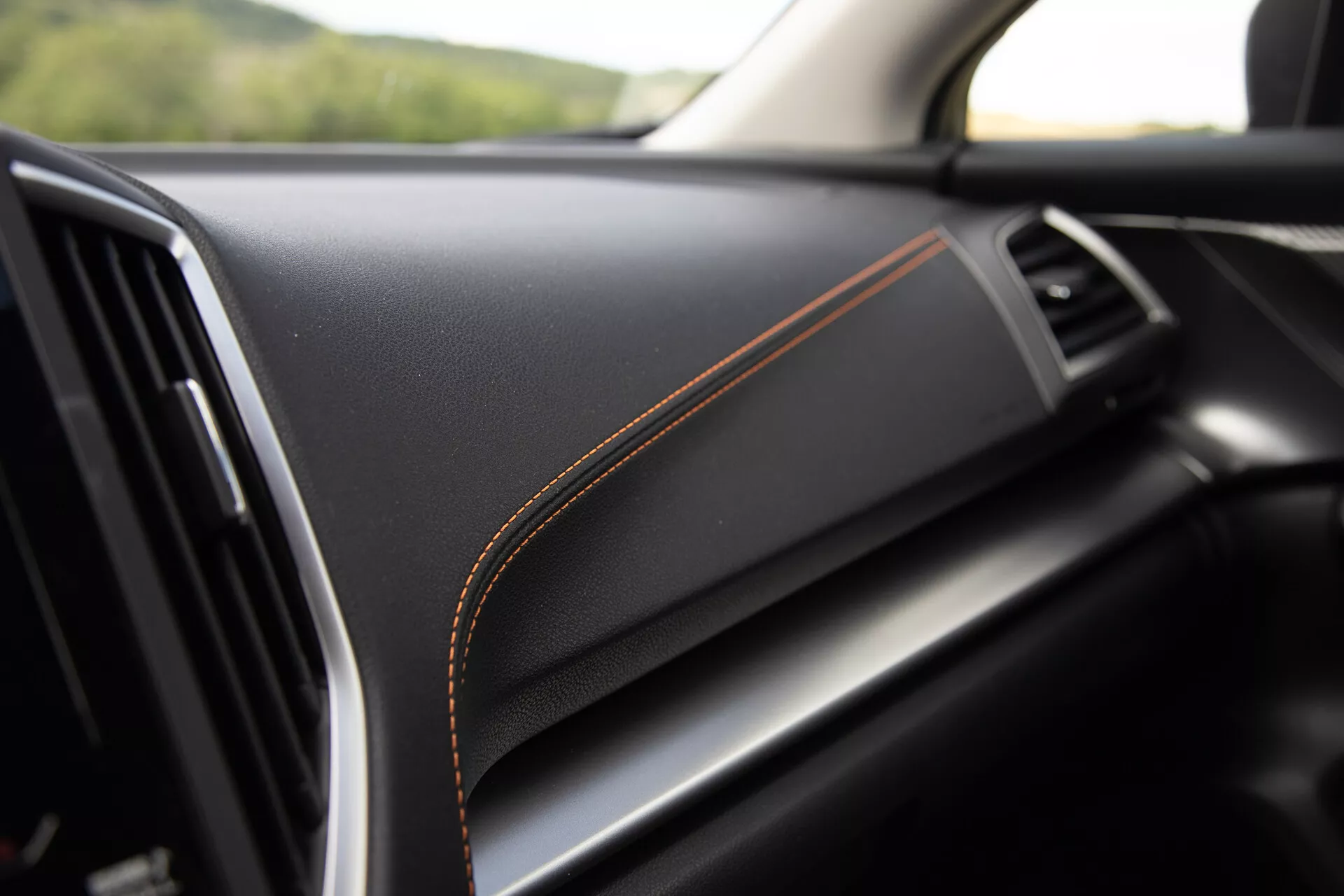 Detail interiéru Subaru XV 2021 s prémiovým černým materiálem palubní desky s kontrastním oranžovým prošíváním, naznačující luxusní provedení a vysokou kvalitu zpracování
