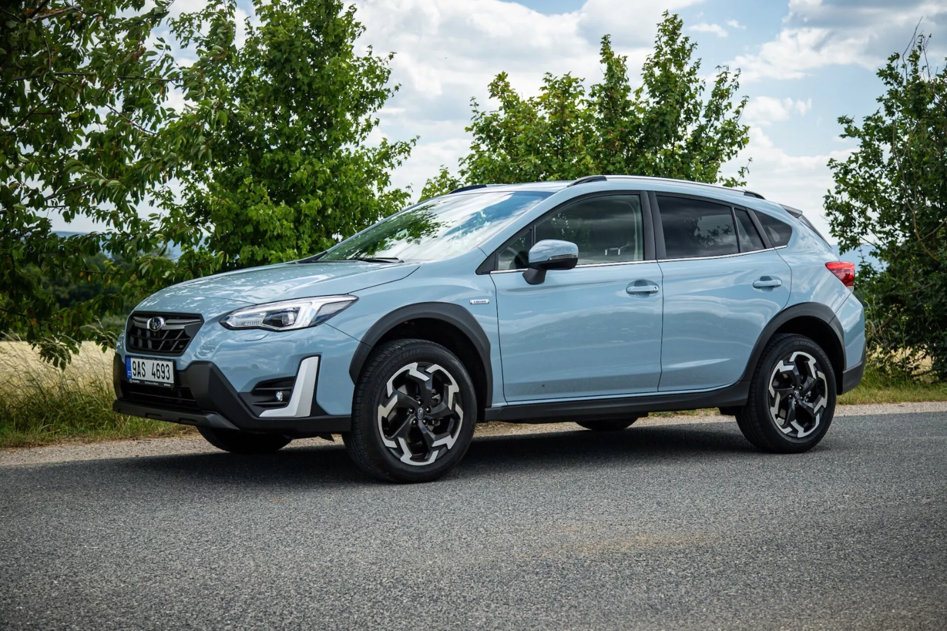 Light blue crossover SUV Subaru XV 2021 zaparkovaný na asfaltu s profilovým záběrem, výraznými černými slitinovými koly, LED zadními světly, vysokou světlou výškou pro městské a mírné terénní použití a moderními bezpečnostními prvky