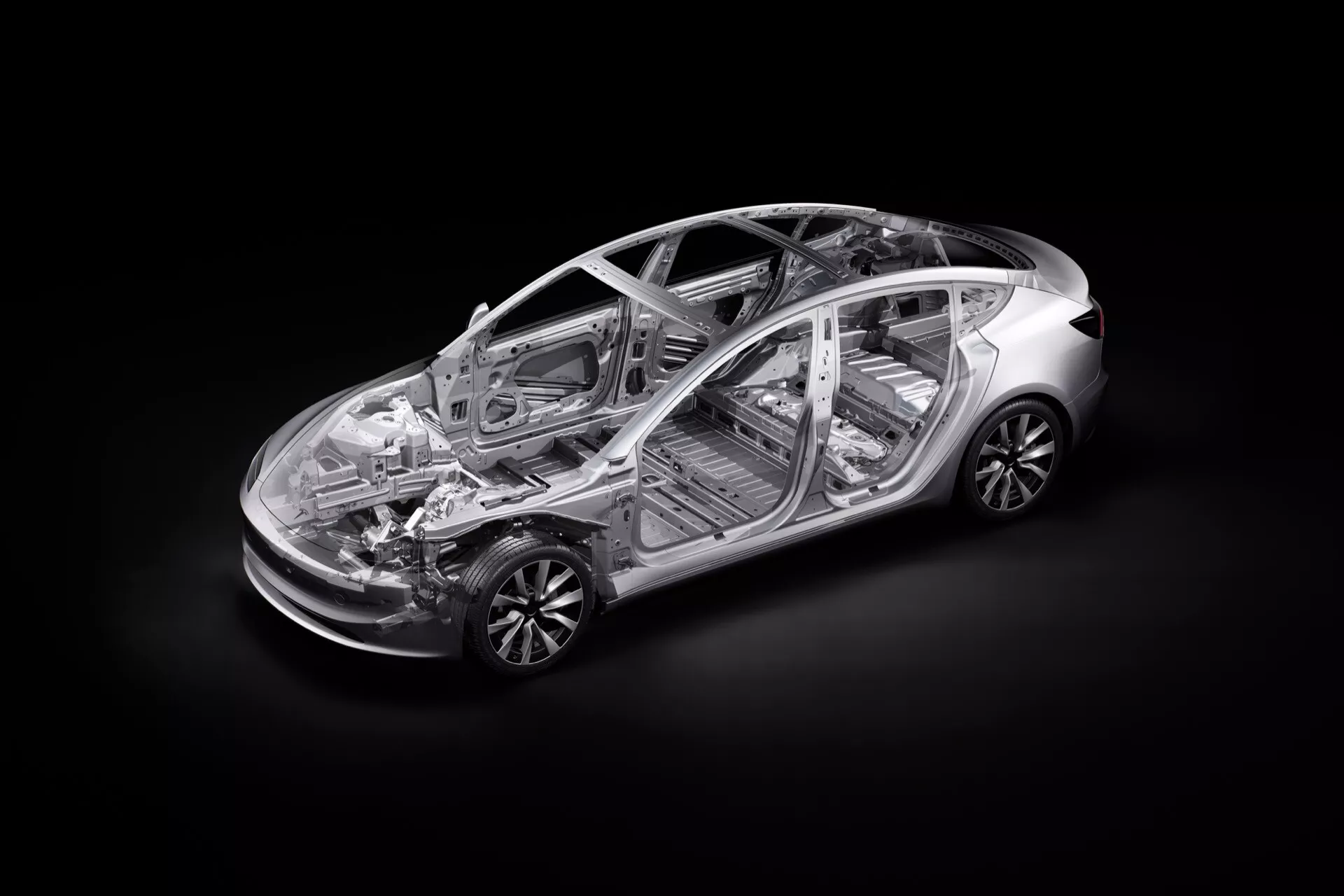Vysokouhlový průhledný pohled na Tesla Model 3 2023 (facelift první generace) ukazující vnitřní strukturu a komponenty včetně podvozku, kabiny pro cestující a části pohonného ústrojí, s detailním zobrazením předního a zadního zavěšení kol, slitinových ráfků a náznakem technologie elektrického pohonu.