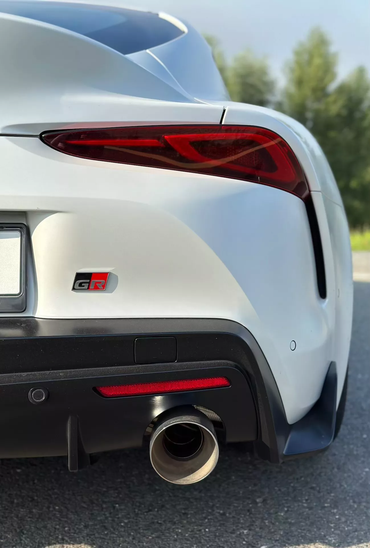 Detailní zobrazení Toyoty Supra GR 2019 s důrazem na pravé LED zadní světlo, odznak GT, sportovní zadní nárazník a výfukový systém v metalickém laku