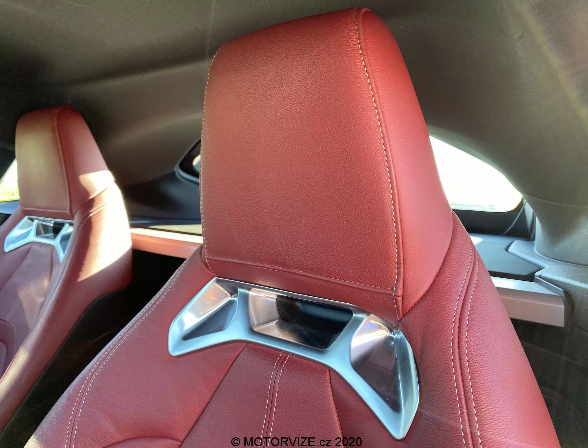 Toyota Supra 2019 GR Supra 2.0 Pure Automatic: Detail luxusního a moderního autosedačky potaženého červenou kůží s viditelným prošitím, s integrovanou opěrkou hlavy s chromovaným dekorativním prvkem, pozorovaný z horního zadního úhlu.