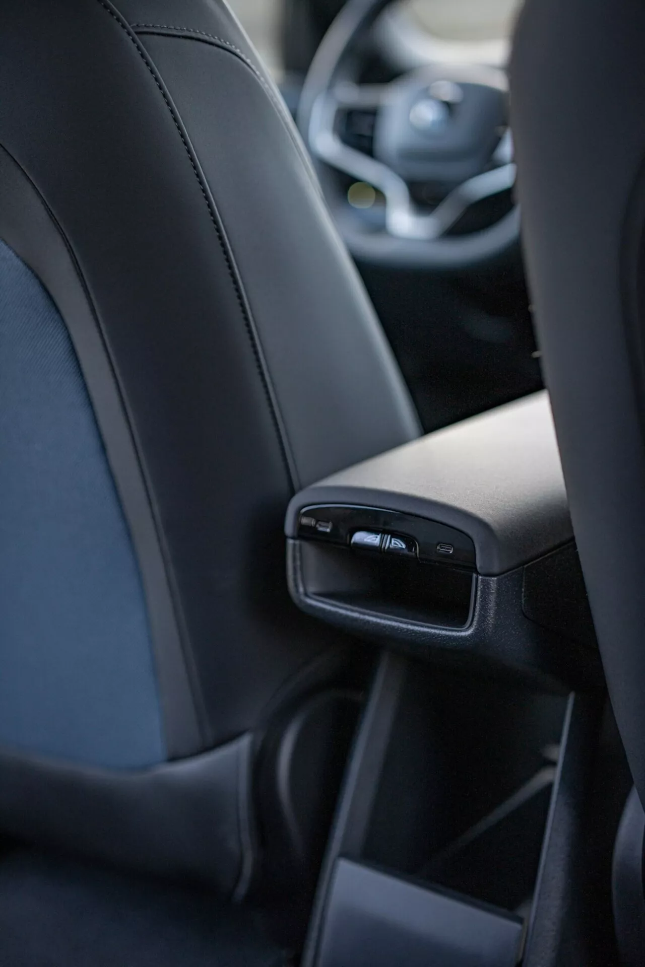 Interiérový pohled na Volvo EX30 2024 zaměřený na detailní prvky zadního středového konzolu z perspektivy zadního středního pasažéra, včetně USB portů a větracích otvorů, představující luxus a technologie