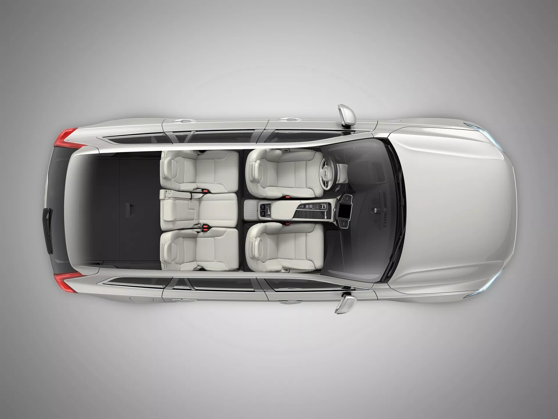 Pohled na Volvo XC90 2015 (2. generace) z ptačí perspektivy, který ukazuje prémiový sedan shora. Úhel poskytuje jasný výhled na střechu, kapotu, kufr a povrchy dveří. Vlastnosti zahrnují dvoupanelové střešní okno nad předními sedadly, interiér světlé barvy s kapacitou pro pět cestujících, litá kola a viditelná boční zrcátka. Zadní okno je strmě skloněné a žádné konkrétní identifikátory značky nejsou viditelné.