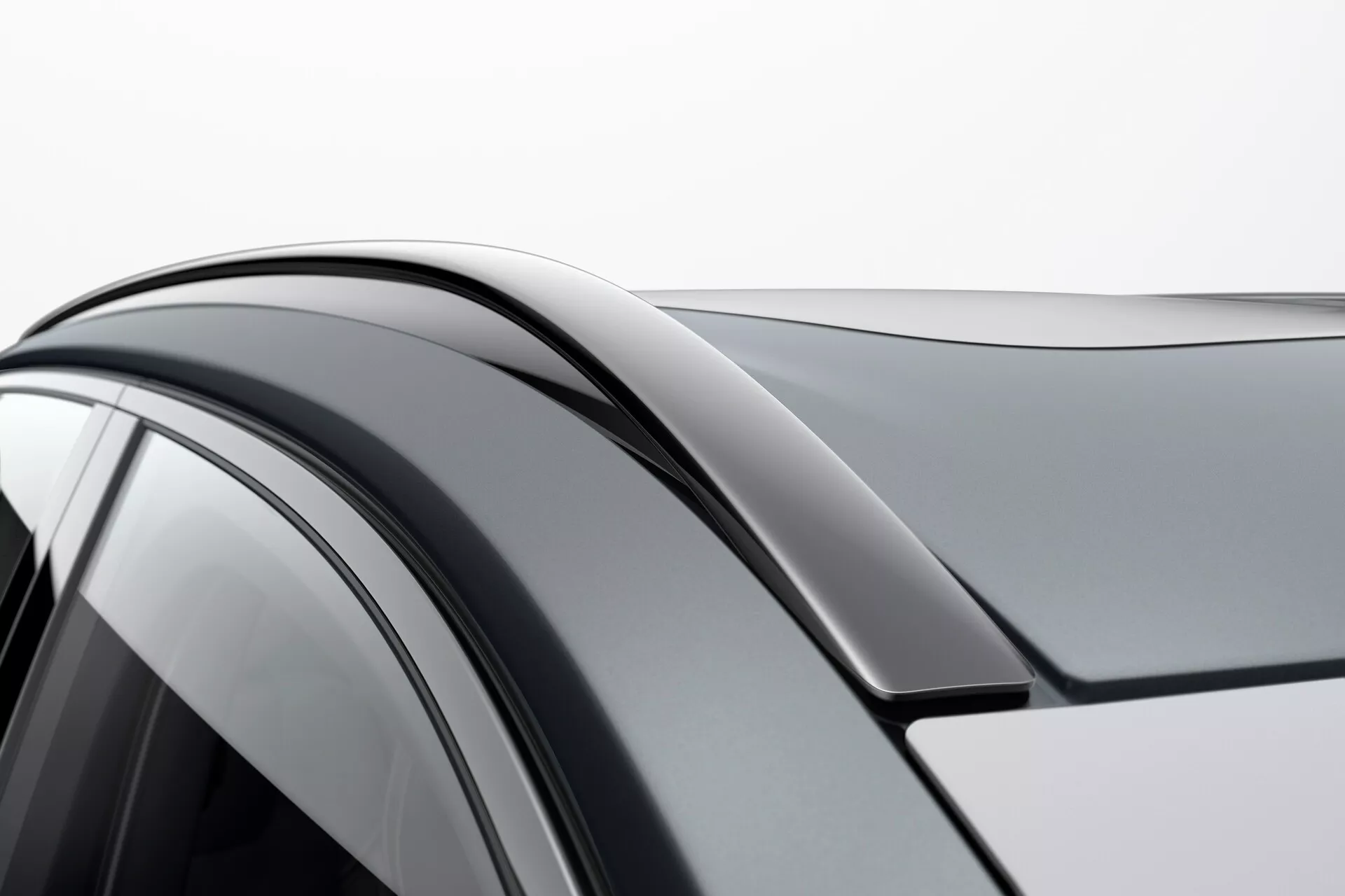 Detailní záběr Volva XC90 2015 druhé generace zaměřený na pravou stranu, zobrazující křivku střechy, horní rám dveří a boční okno s tónovaným sklem; zdůrazňující hladký přechod a aerodynamický design.