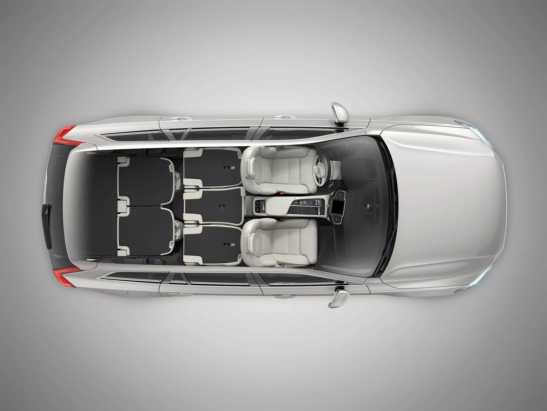 Pohled z ptačí perspektivy na Volvo XC90 2015 druhé generace, ukazující černou střechu a kovově stříbrné nebo šedé tělo s panoramatickou střechou, zavřené dveře a okna. Jasně vidíte kola a design ráfků a také boční zrcátka, což zdůrazňuje bezpečnost a exteriérové funkce. Zúžený tvar střechy vzadu naznačuje, že by to mohl být čtyřdveřový sedan nebo kupé.