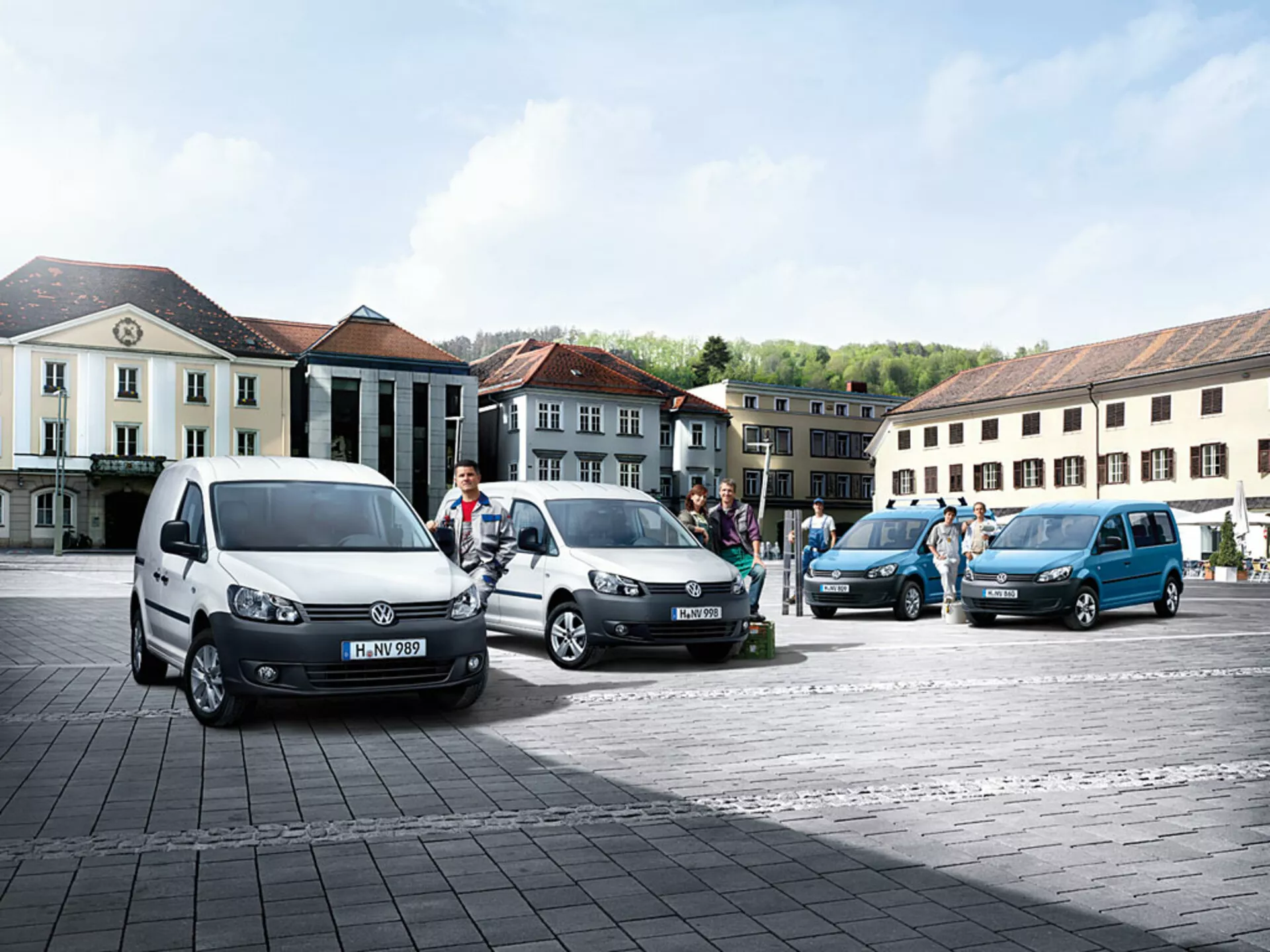 Víceúčelové dodávky Volkswagen Caddy 2010 zaparkované v diagonální linii na dlažebním náměstí, předvádějící různé barvy a úhly, s viditelnými charakteristickými předními a bočními profily
