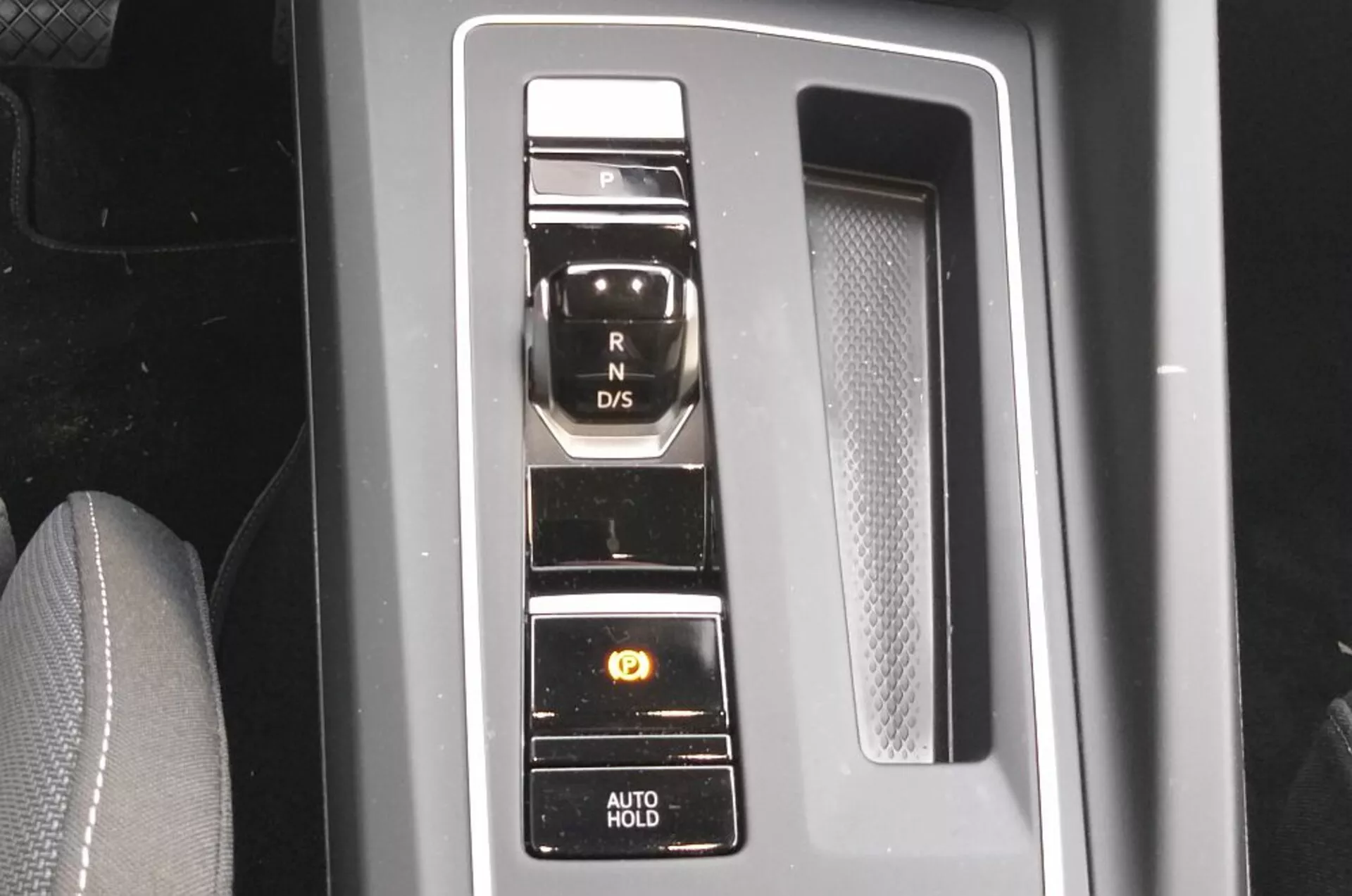 Detailní pohled na elektronický volič převodových stupňů VW Golf GTD 2017 s vertikálním uspořádáním tlačítek na černém lesklém panelu s chromovými prvky, prezentující moderní technologii přenosového systému a pohodlné funkce jako je parkovací brzda a funkce AUTO HOLD