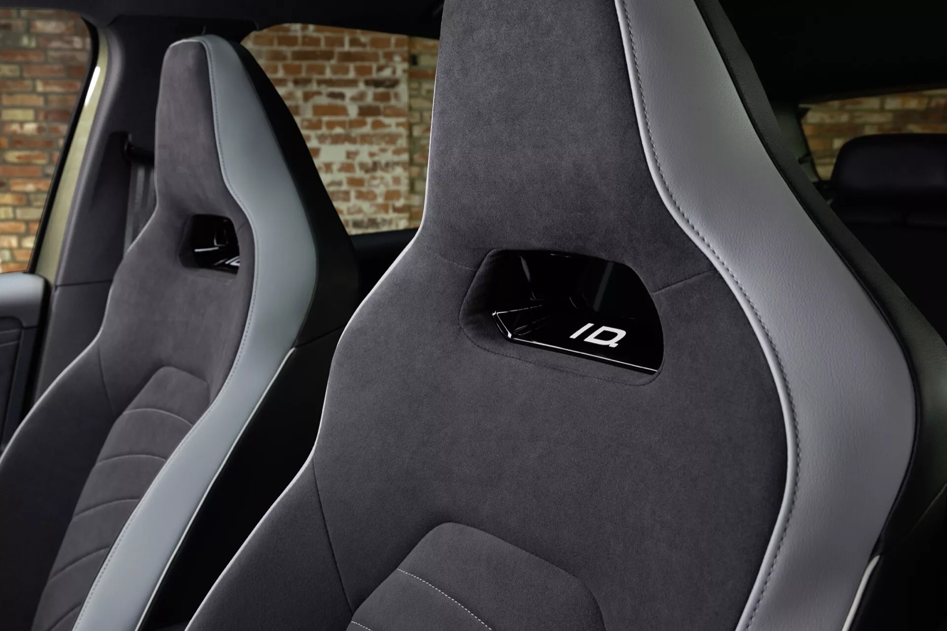 Interiér VW ID3 1. generace facelift 2023 s předními sportovními sedadly s tmavou barvou a světle šedými akcenty, integrovanými opěrkami hlavy s logem ID, v prémiovém potahu z semiše nebo Alcantary